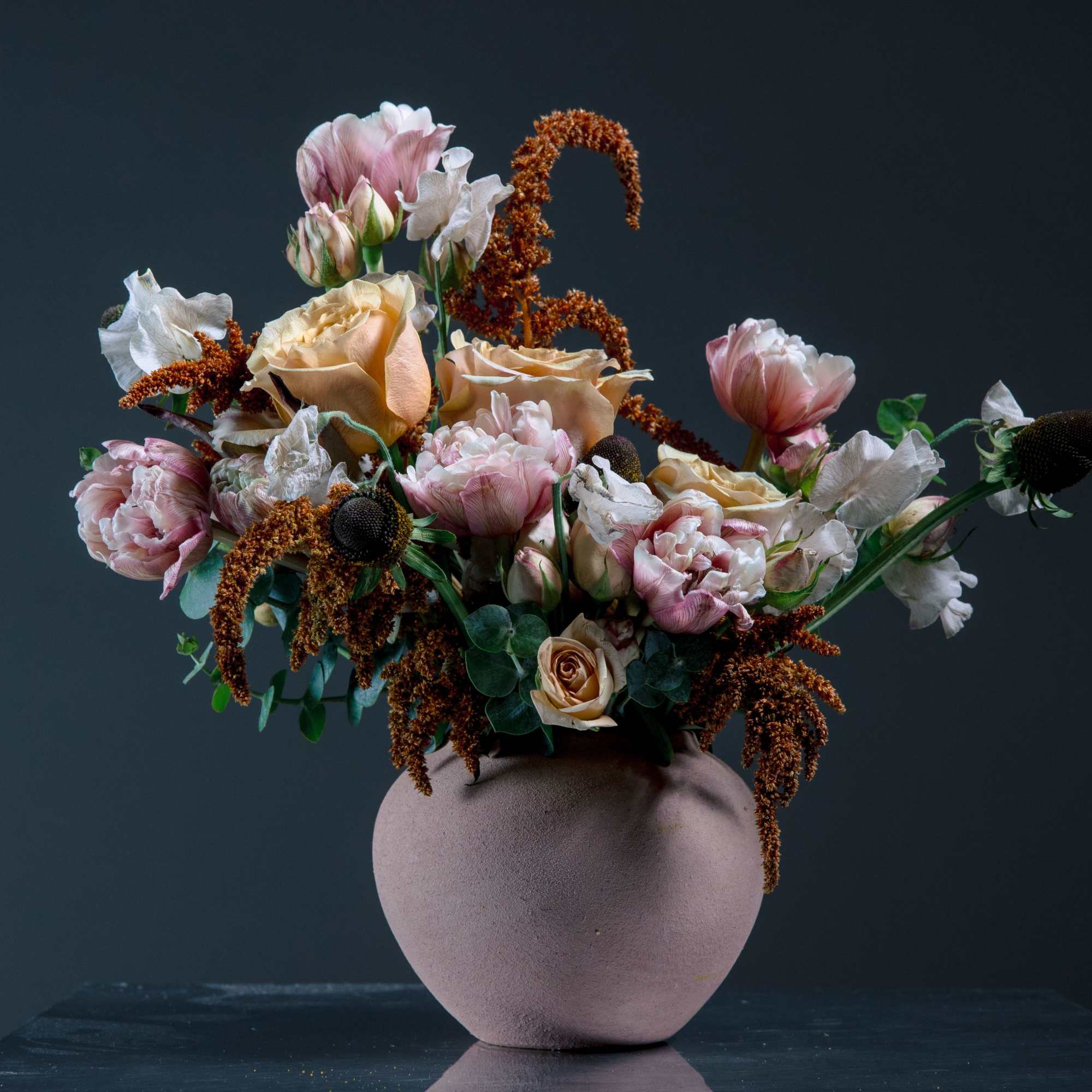A sculptural vase arrangement in soft peach, blush pink, and ivory that
