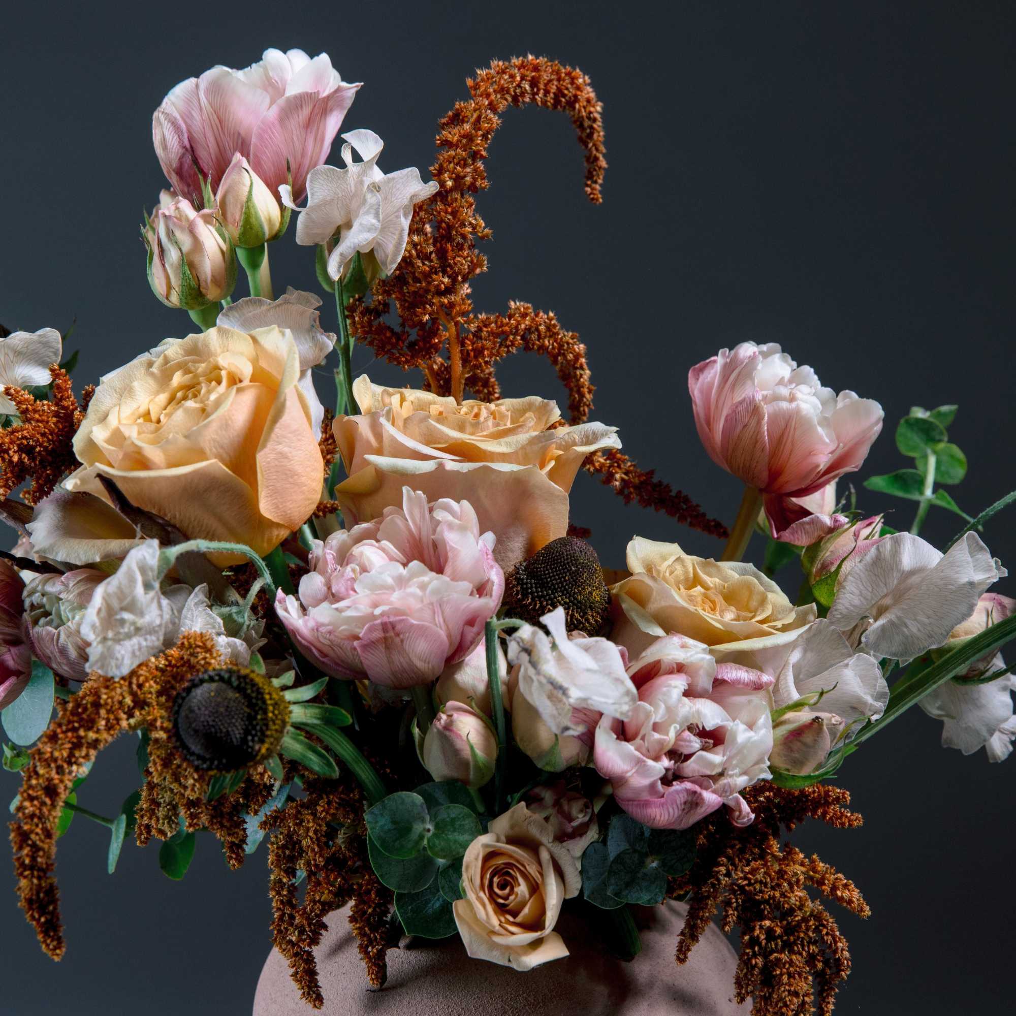 A sculptural vase arrangement in soft peach, blush pink, and ivory that