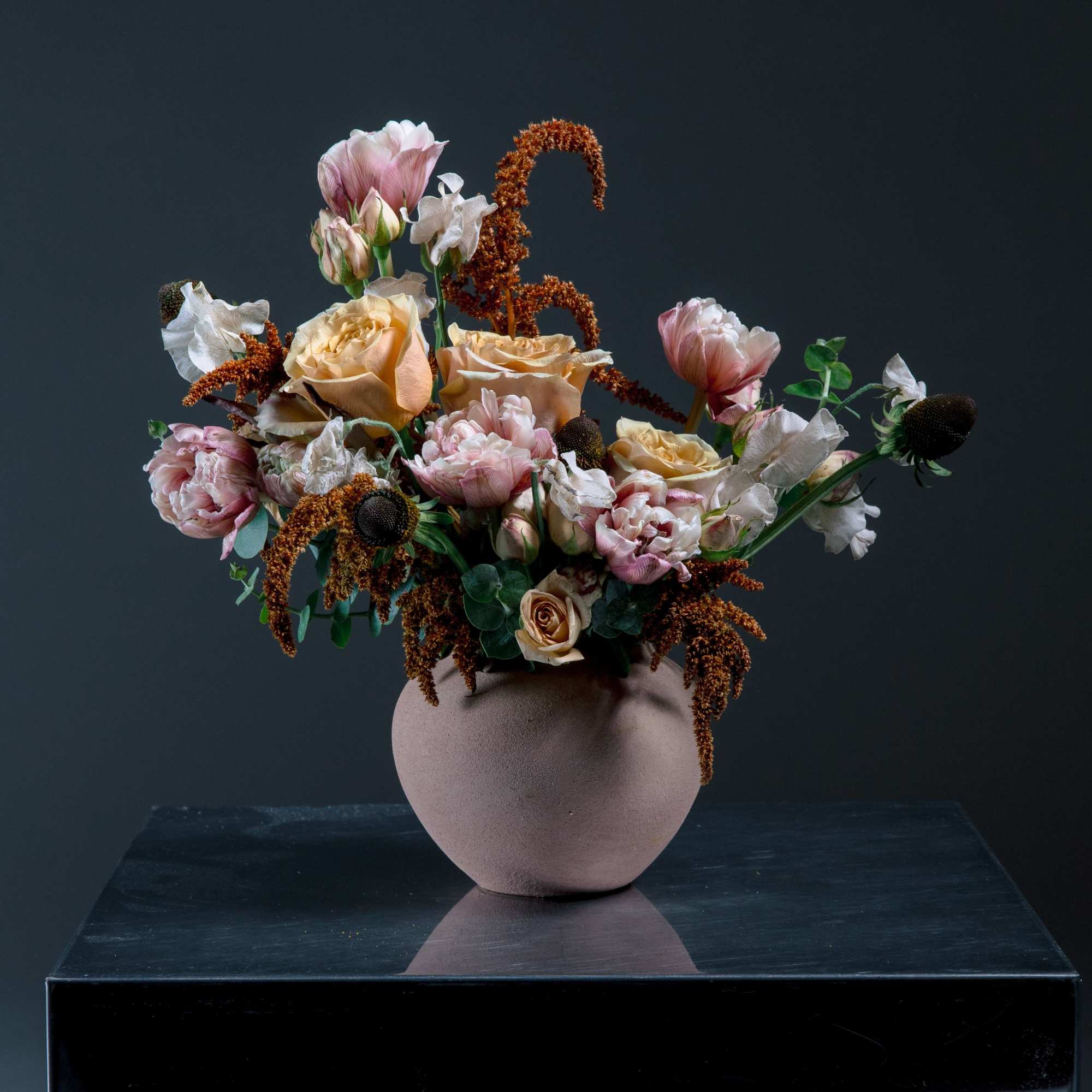 A sculptural vase arrangement in soft peach, blush pink, and ivory that