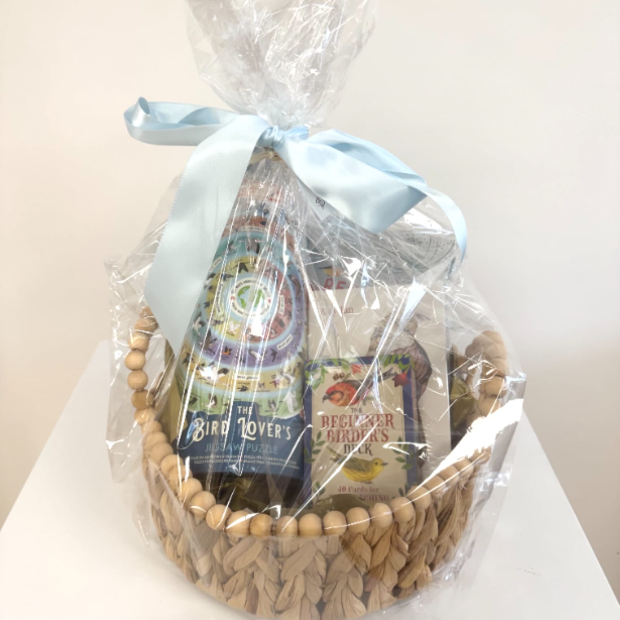 Gift basket with bird-themed books wrapped in clear cellophane and a blue ribbon