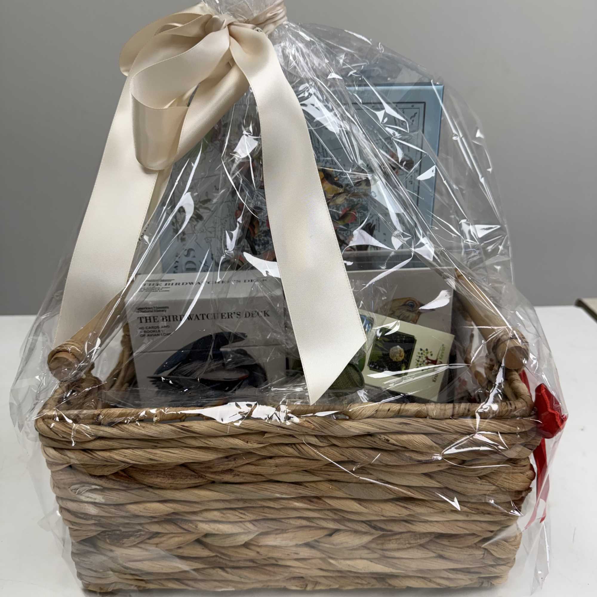 Gift basket wrapped in clear cellophane with a cream ribbon