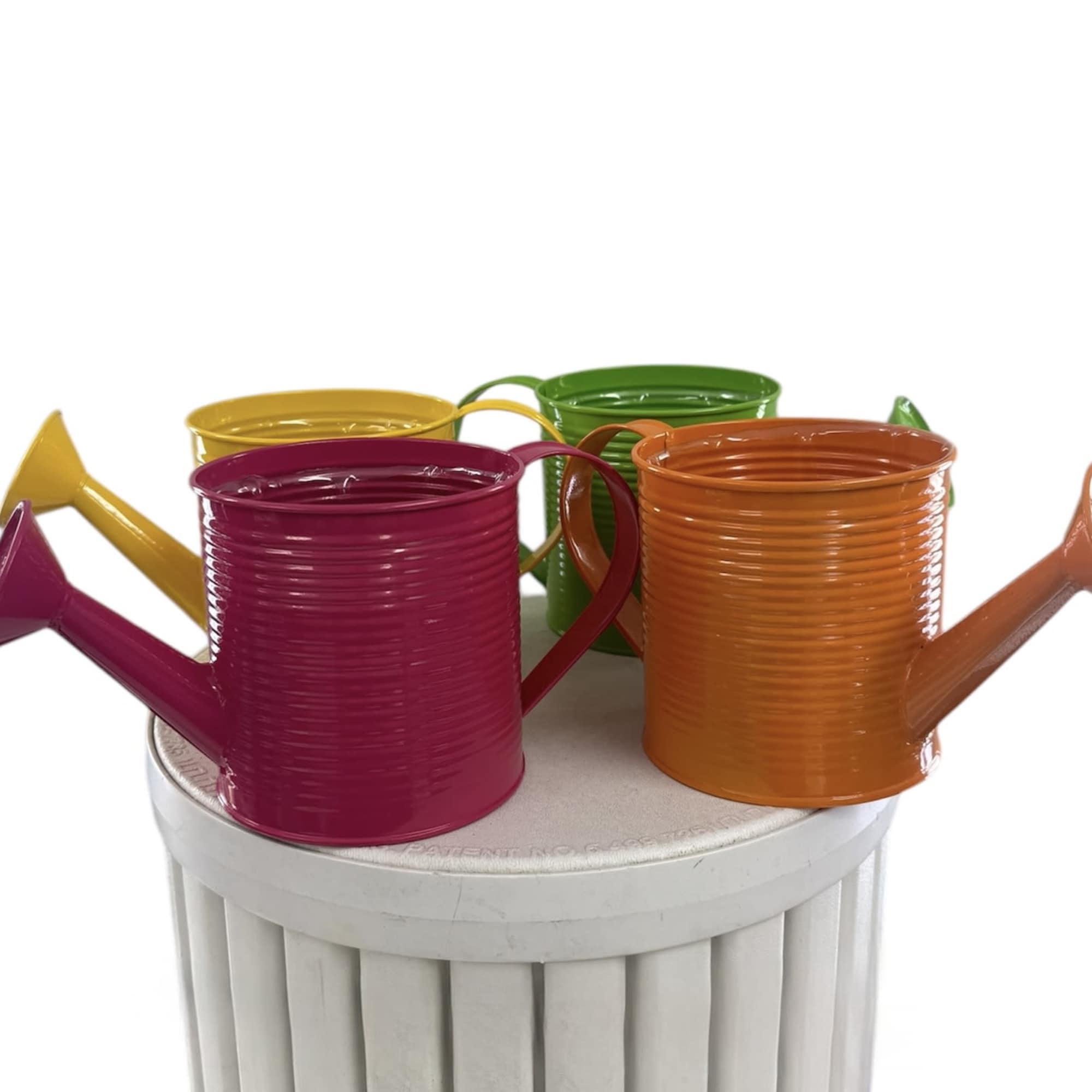 Colorful metal watering cans arranged on a white pedestal
