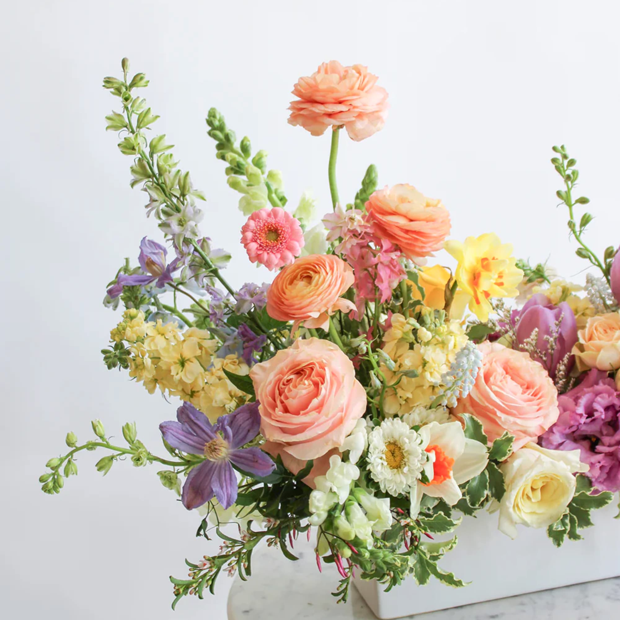 Mixed pastel flower arrangement in a white rectangular vase