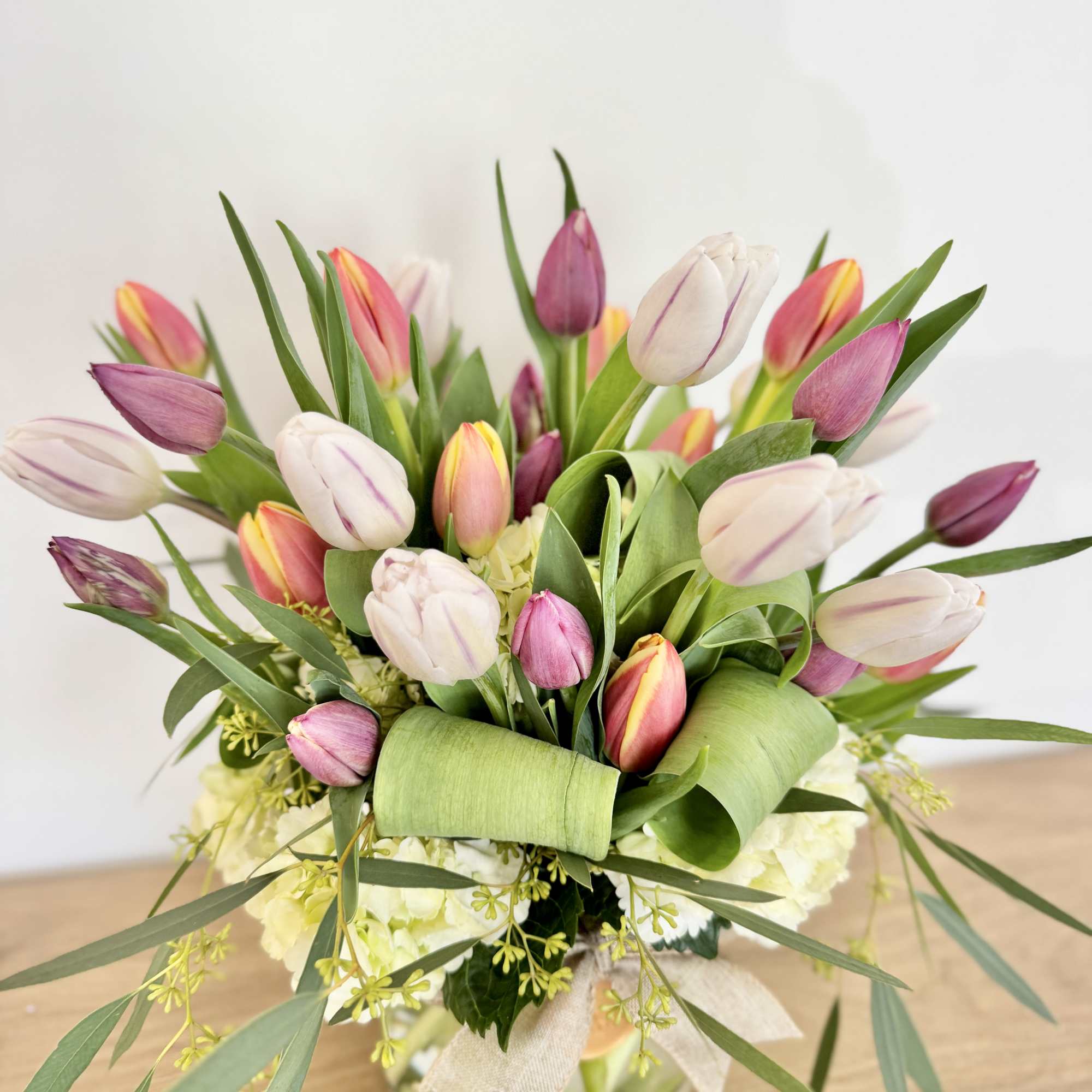 Bouquet of pink, white, and yellow tulips in a glass vase