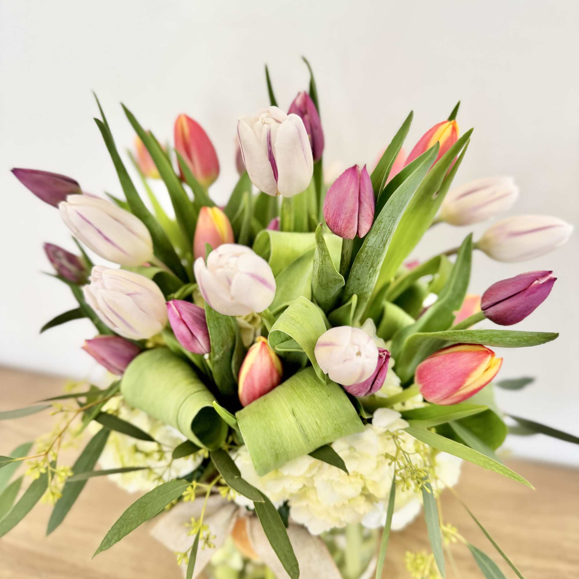 Bouquet of pink, white, and purple tulips with green foliage