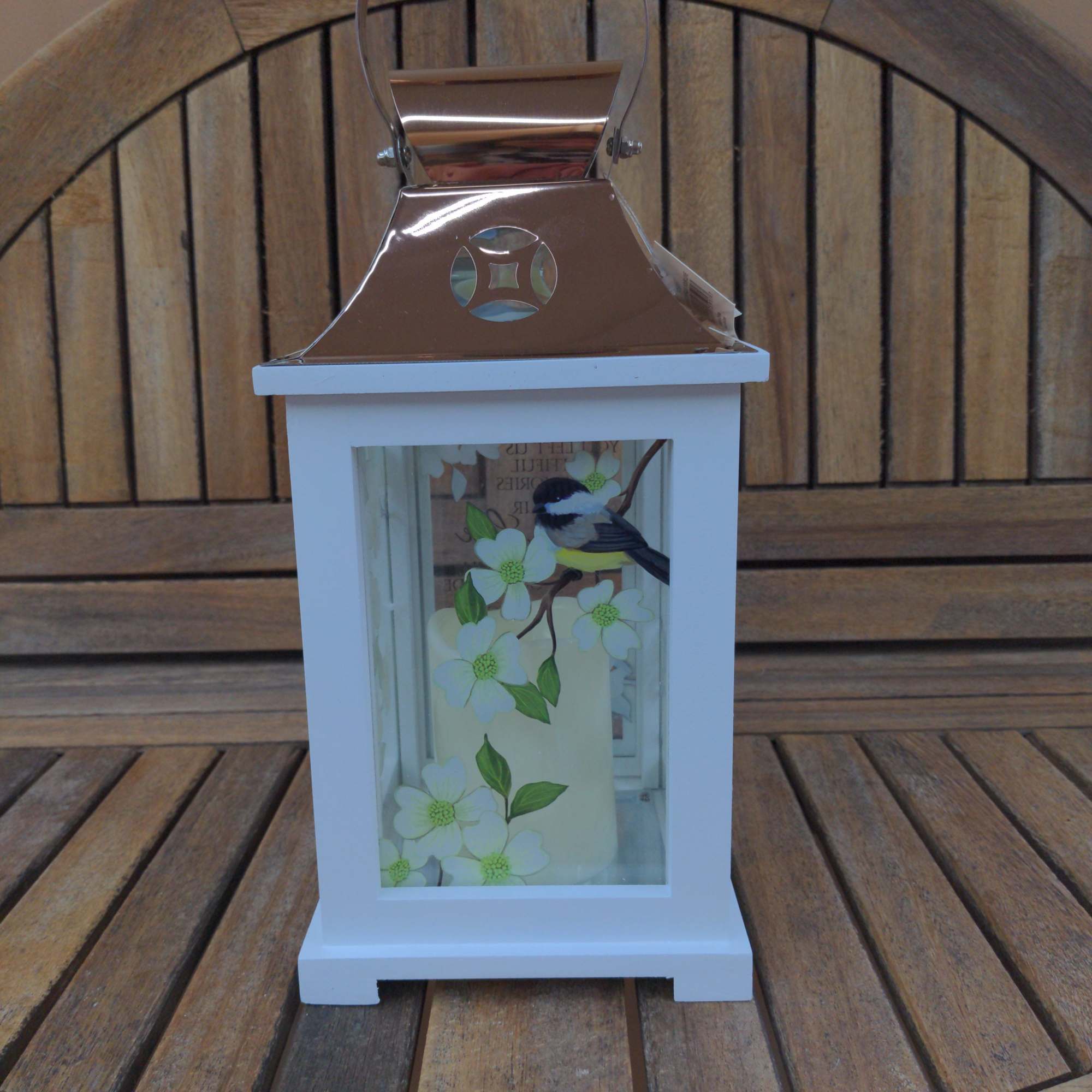 White lantern with floral cutout design and a metal handle