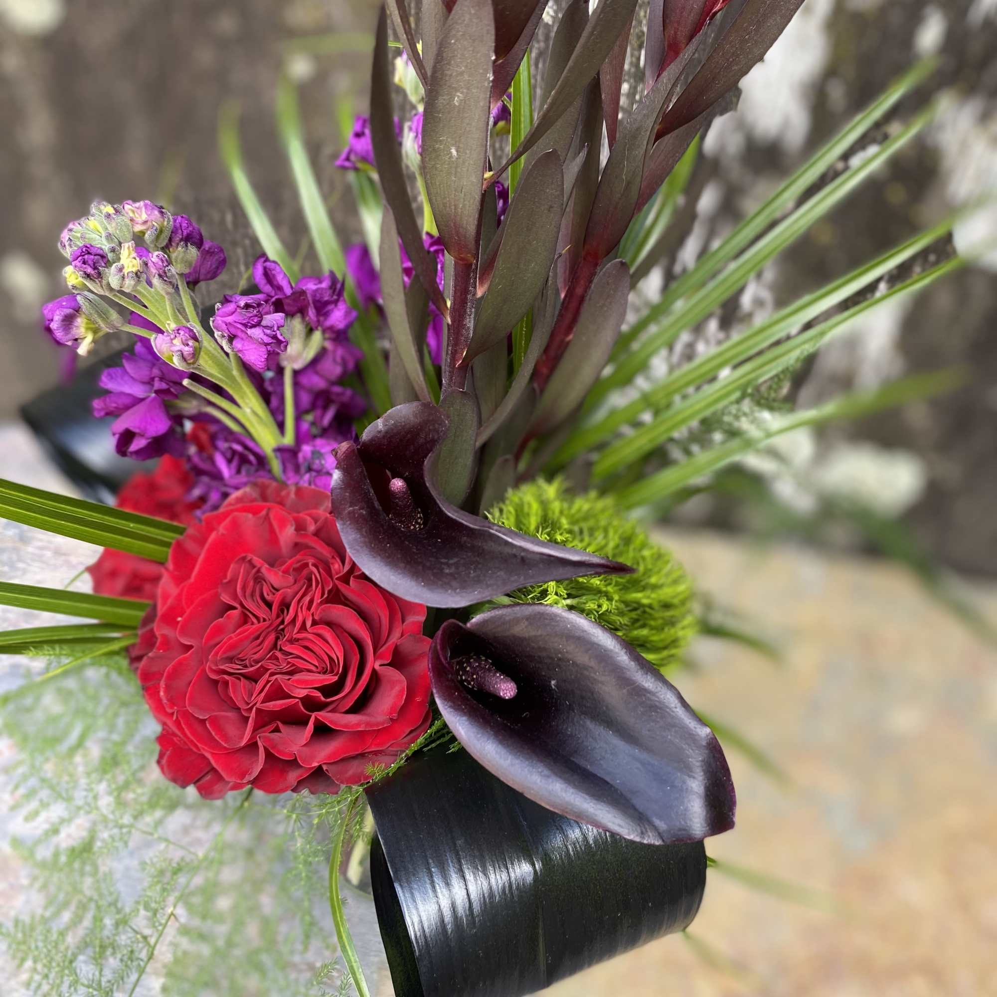 Bouquet with red roses, black calla lilies, and purple flowers