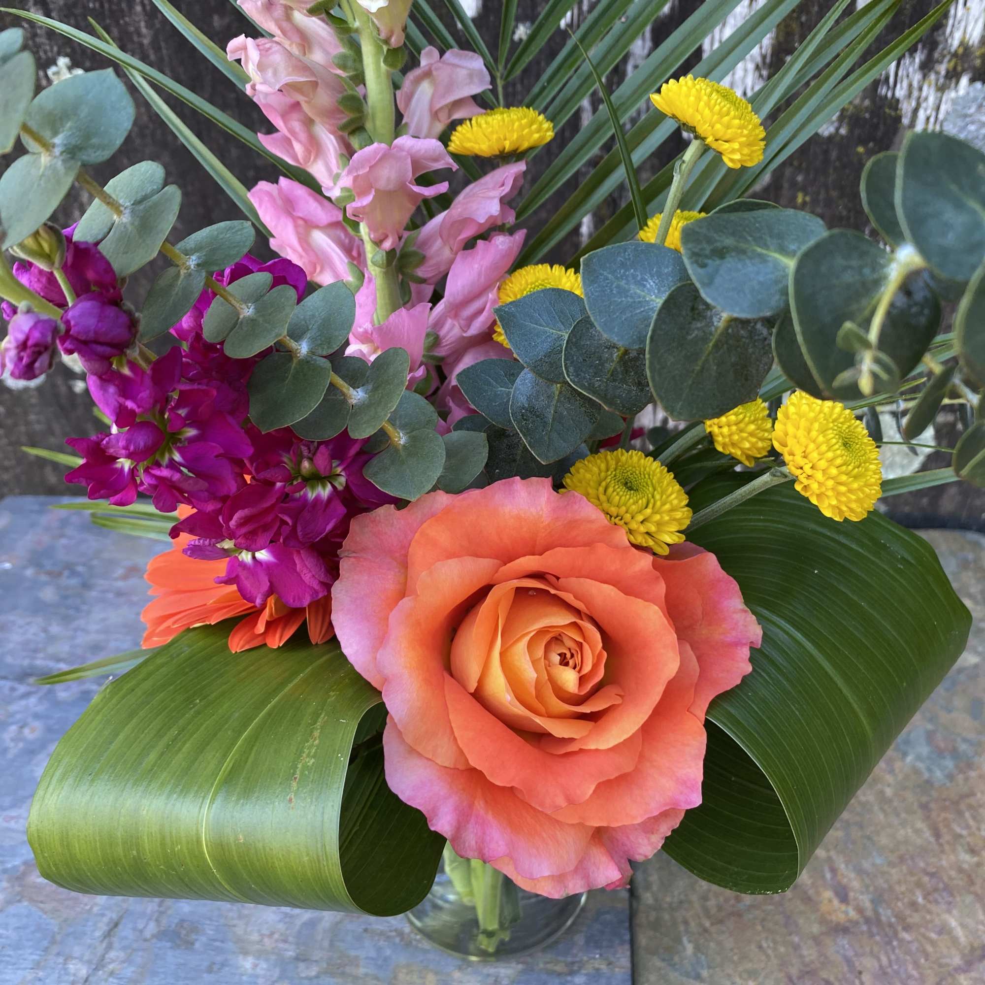 Mixed bouquet with a peach rose, pink snapdragons, and yellow button mums