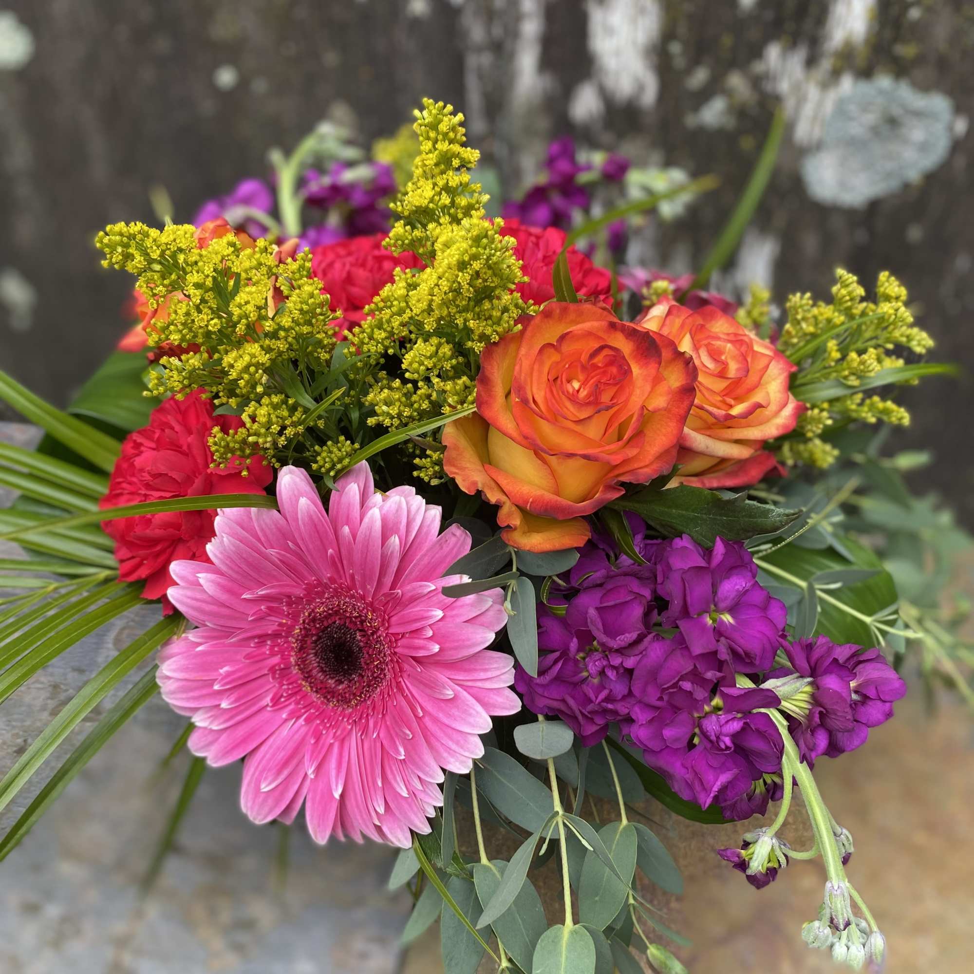 Mixed bouquet with pink gerbera, orange roses, and purple blooms