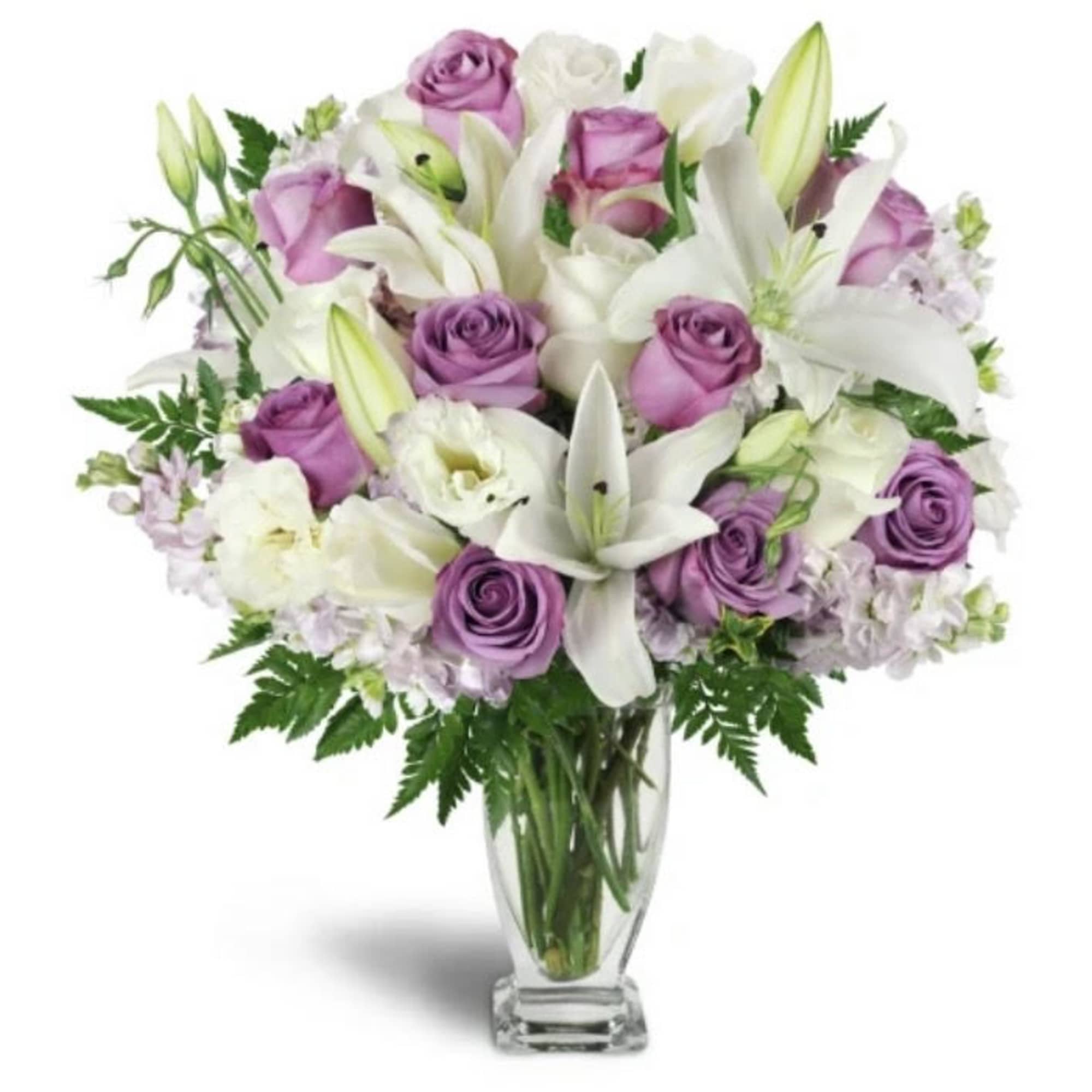 Lavender roses and white lilies arranged in a clear glass vase