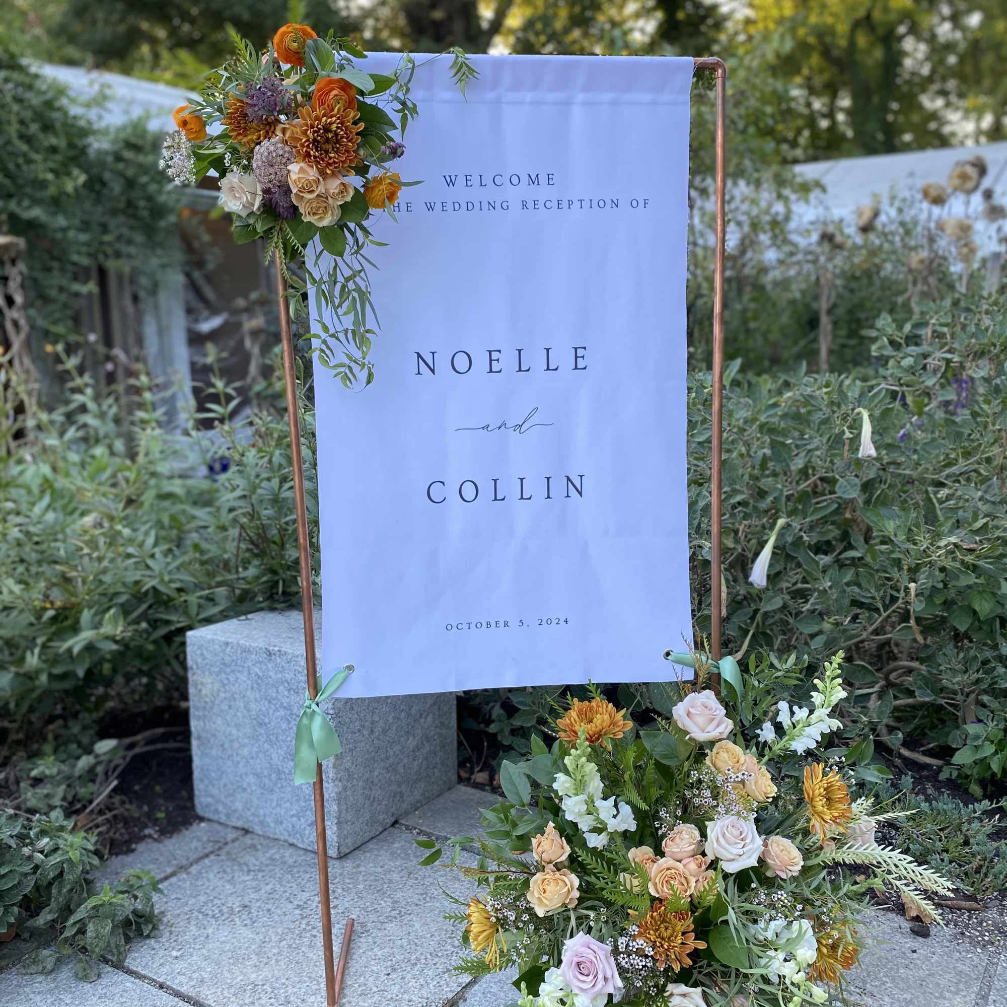 Event signage with flower arrangement(s)