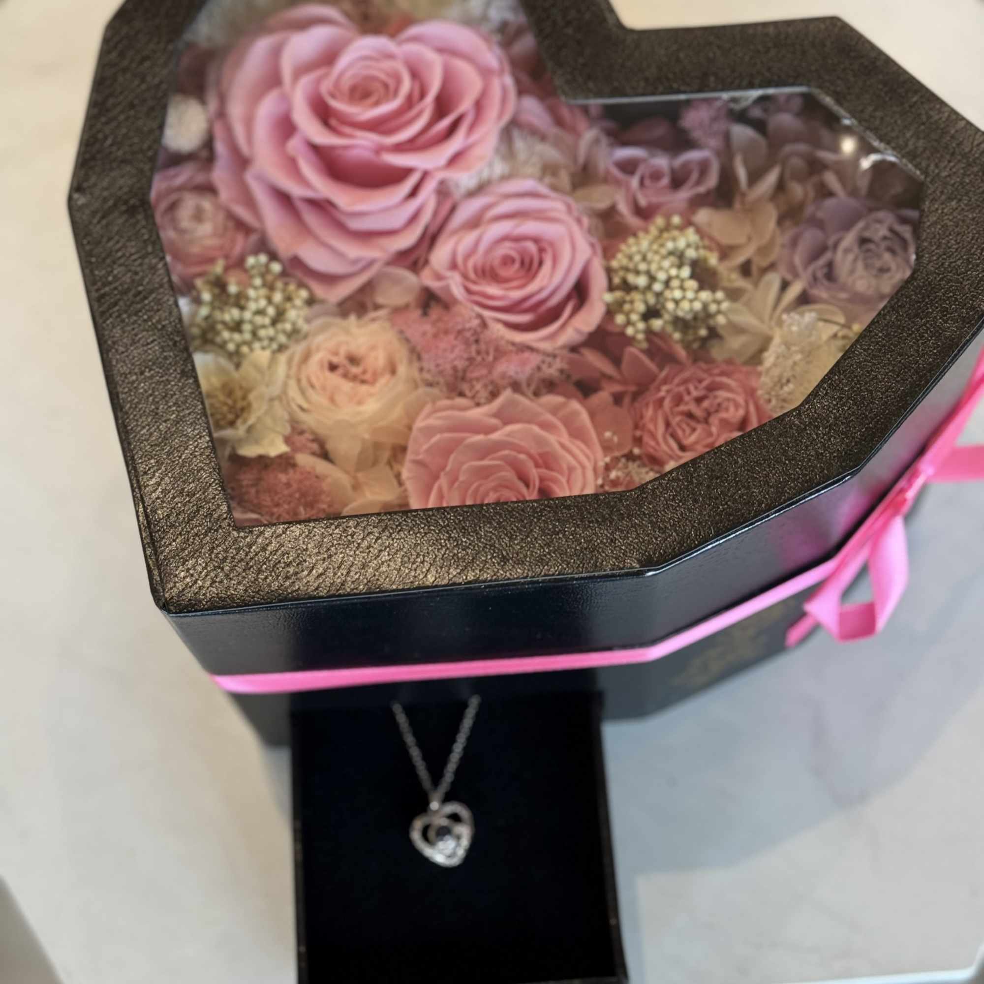 A heart-shaped black gift box reveals a keepsake of preserved roses and