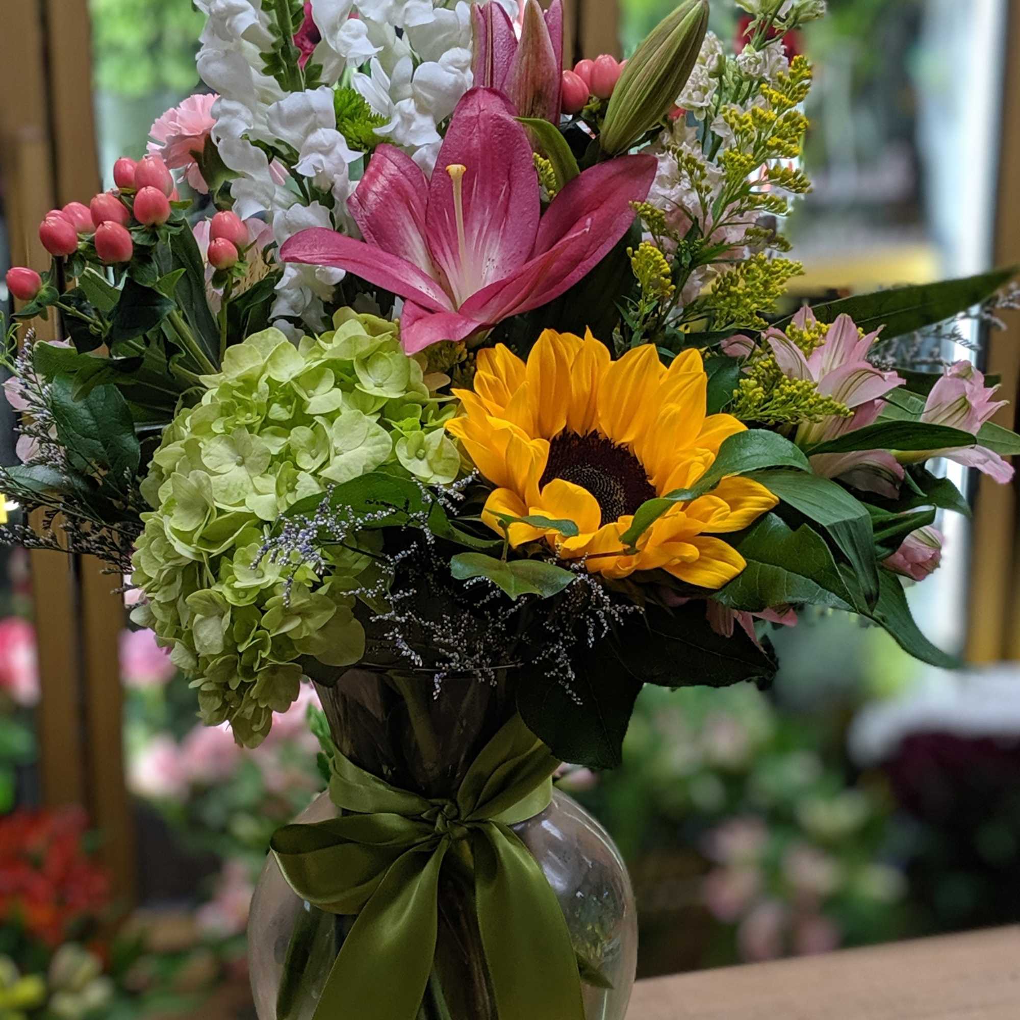 Mixed bouquet in a glass vase with sunflowers, lilies, and hydrangeas