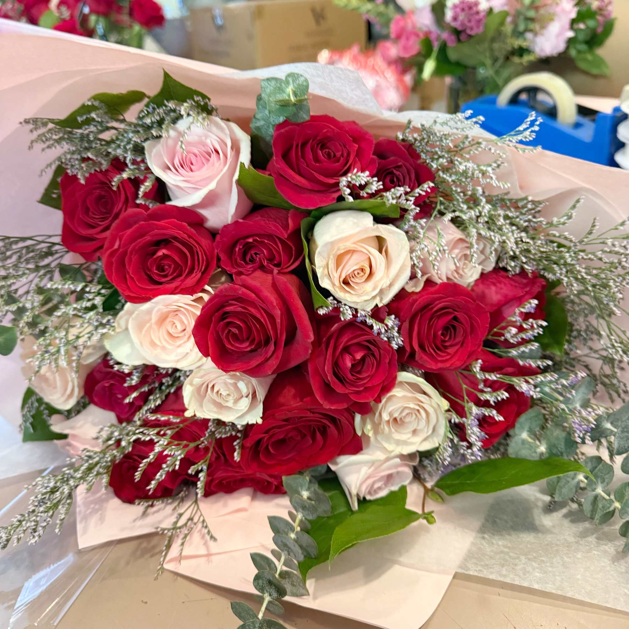 Bouquet of red and blush roses wrapped in pale pink paper