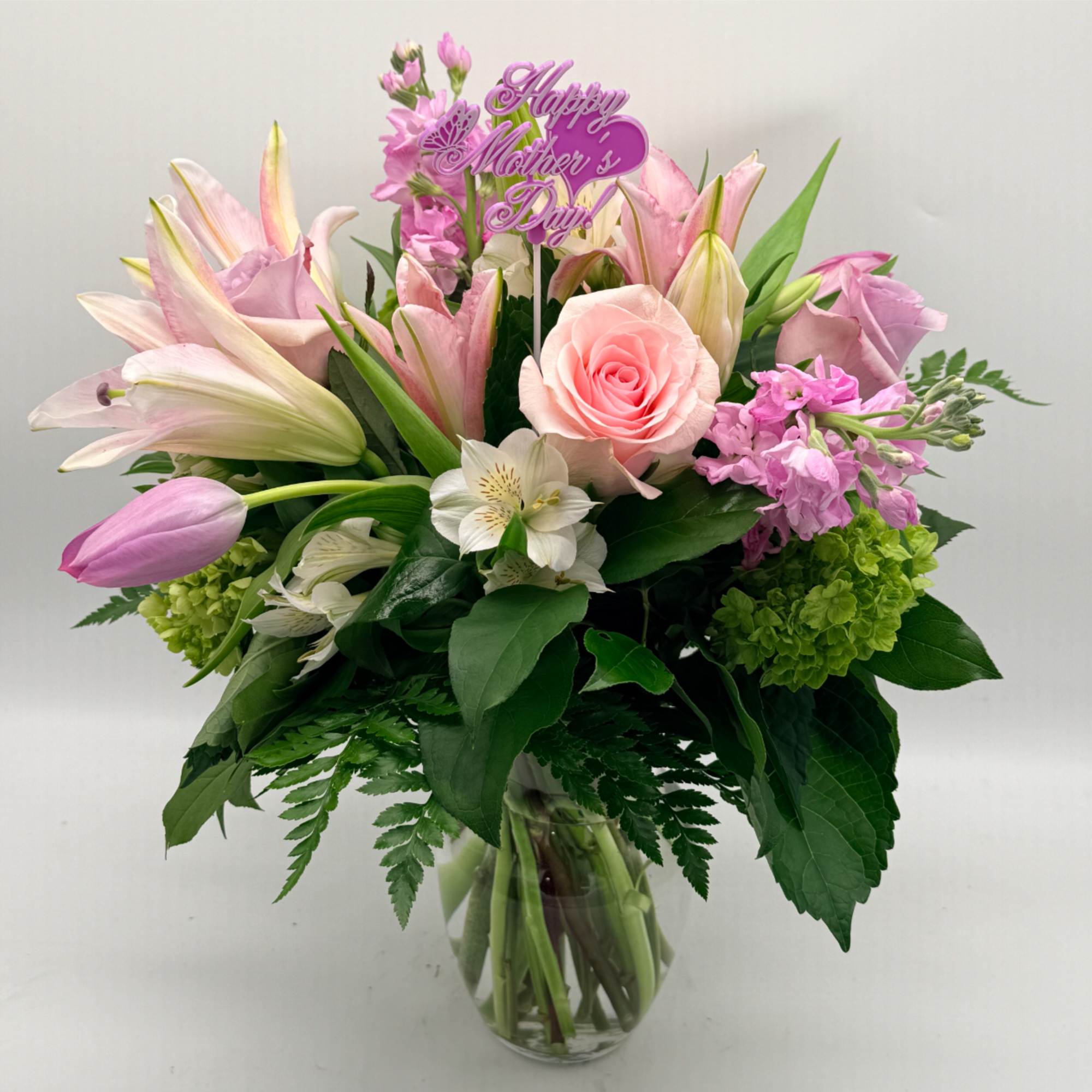 Soft, romantic, and effortlessly graceful, this garden-style arrangement features  lilies, roses