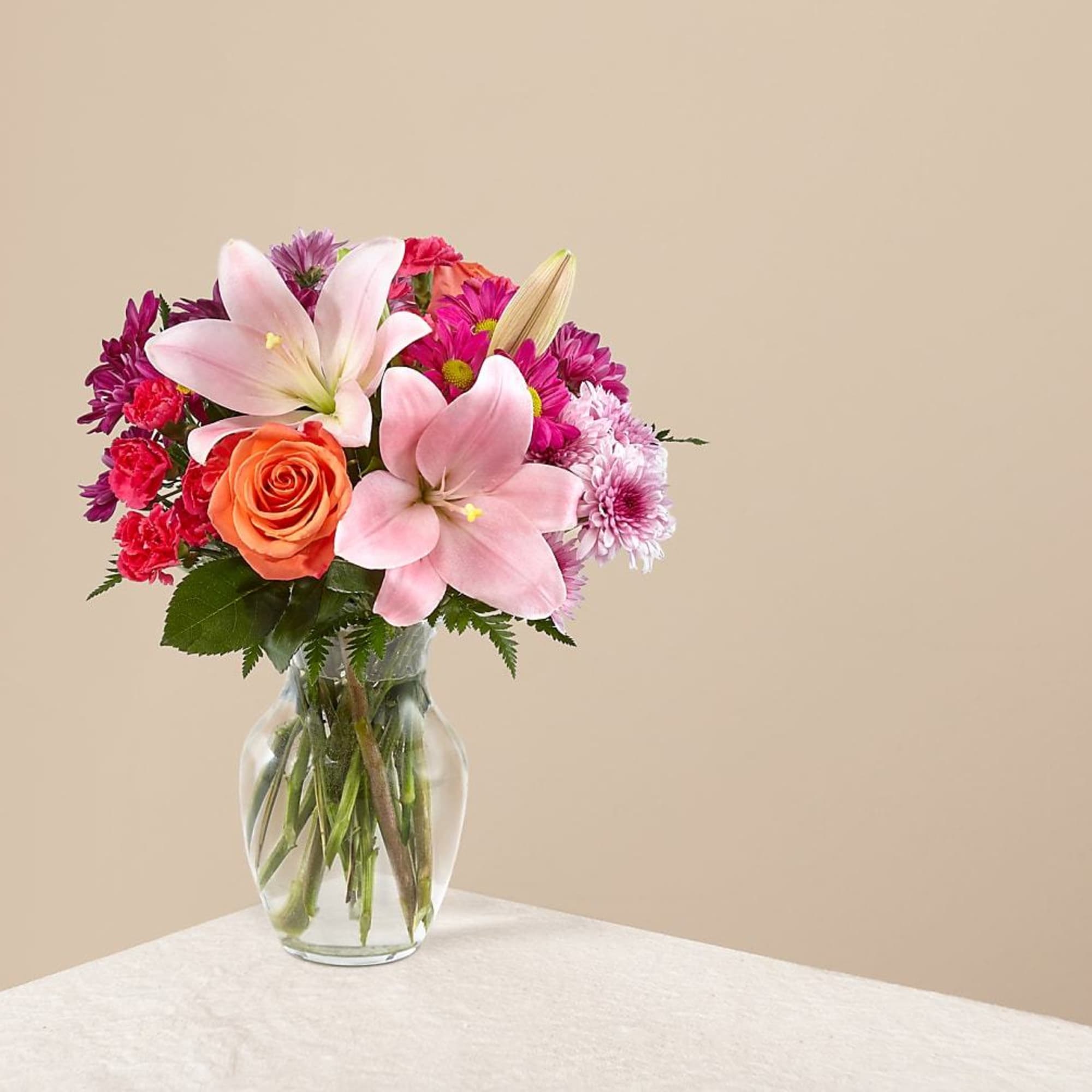 Pink and orange flower bouquet in a clear glass vase