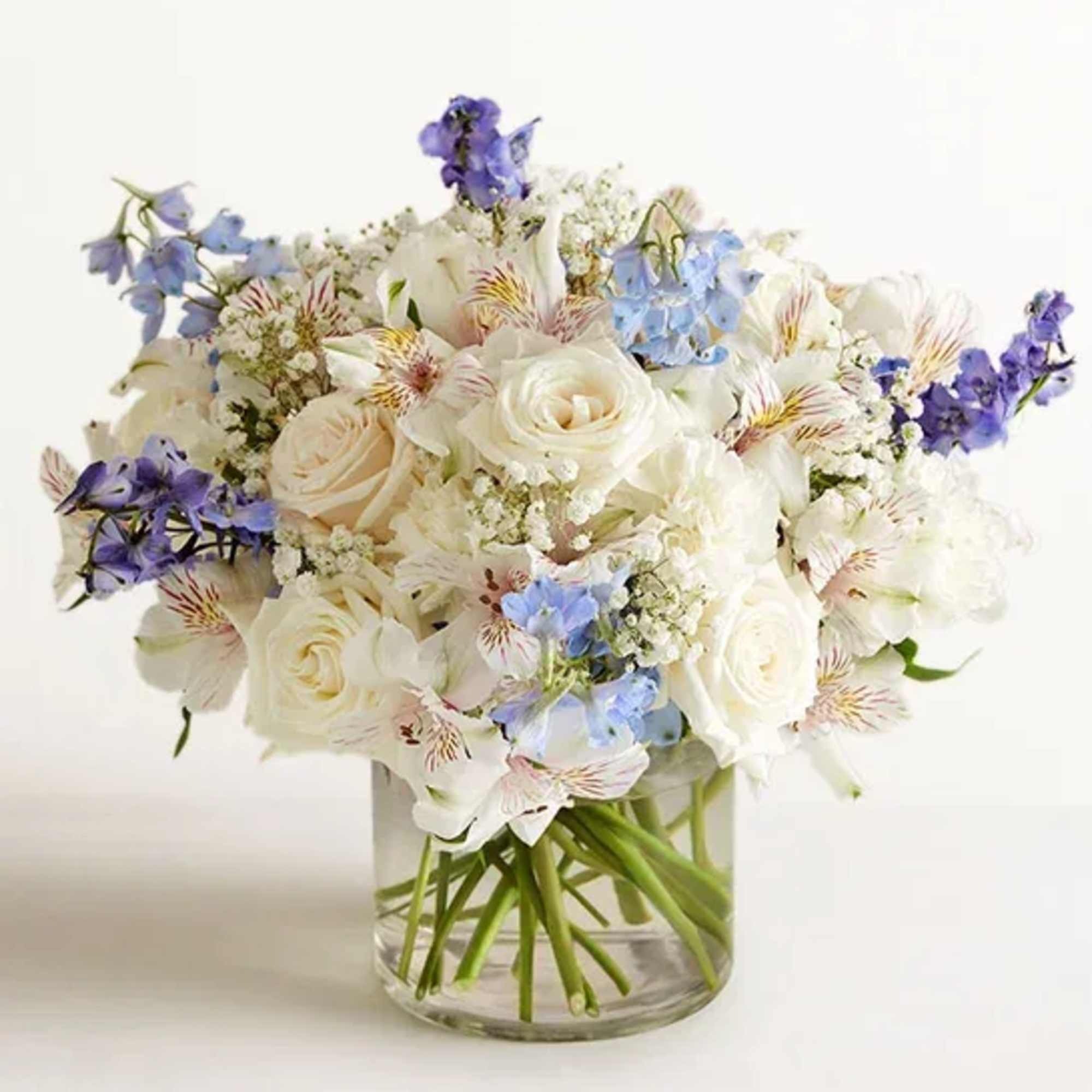 White and pale blue bouquet in a clear glass vase