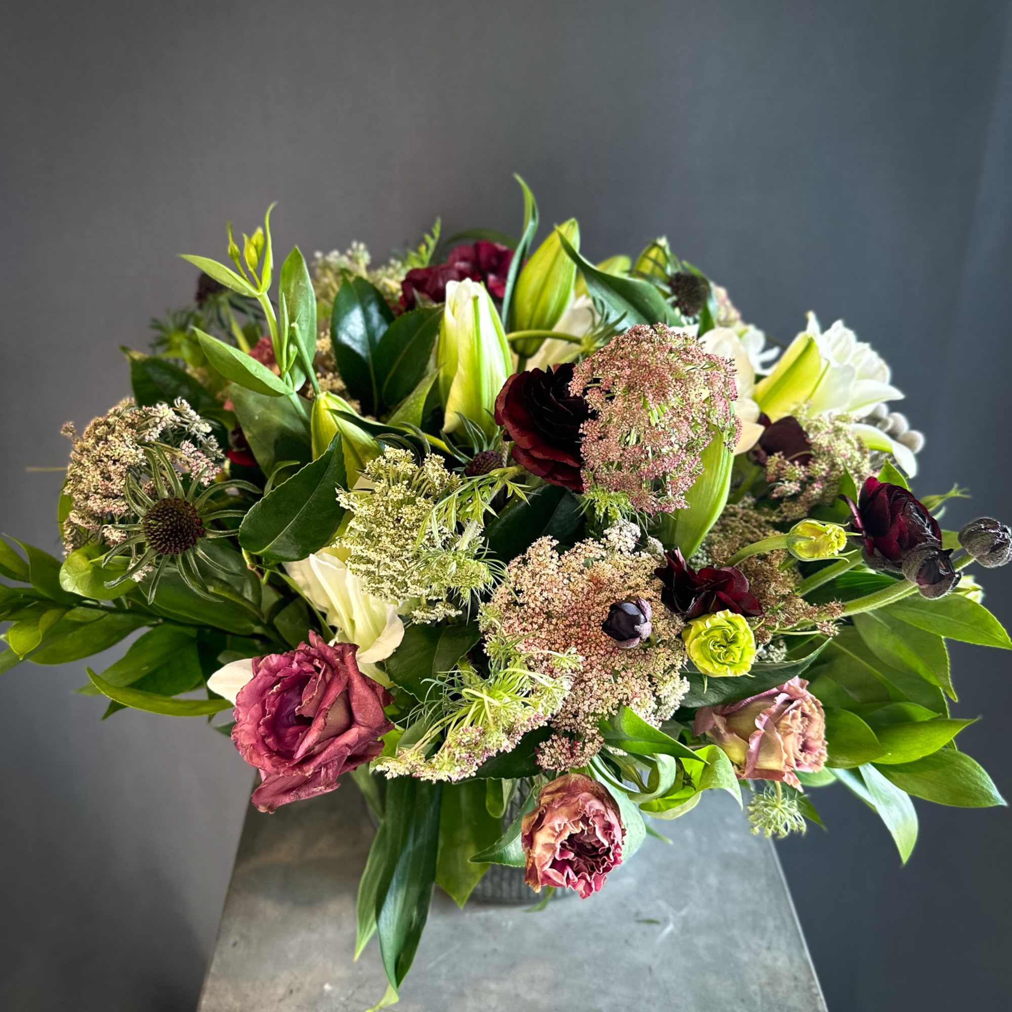 Mixed bouquet with lilies, roses, and dark burgundy blooms