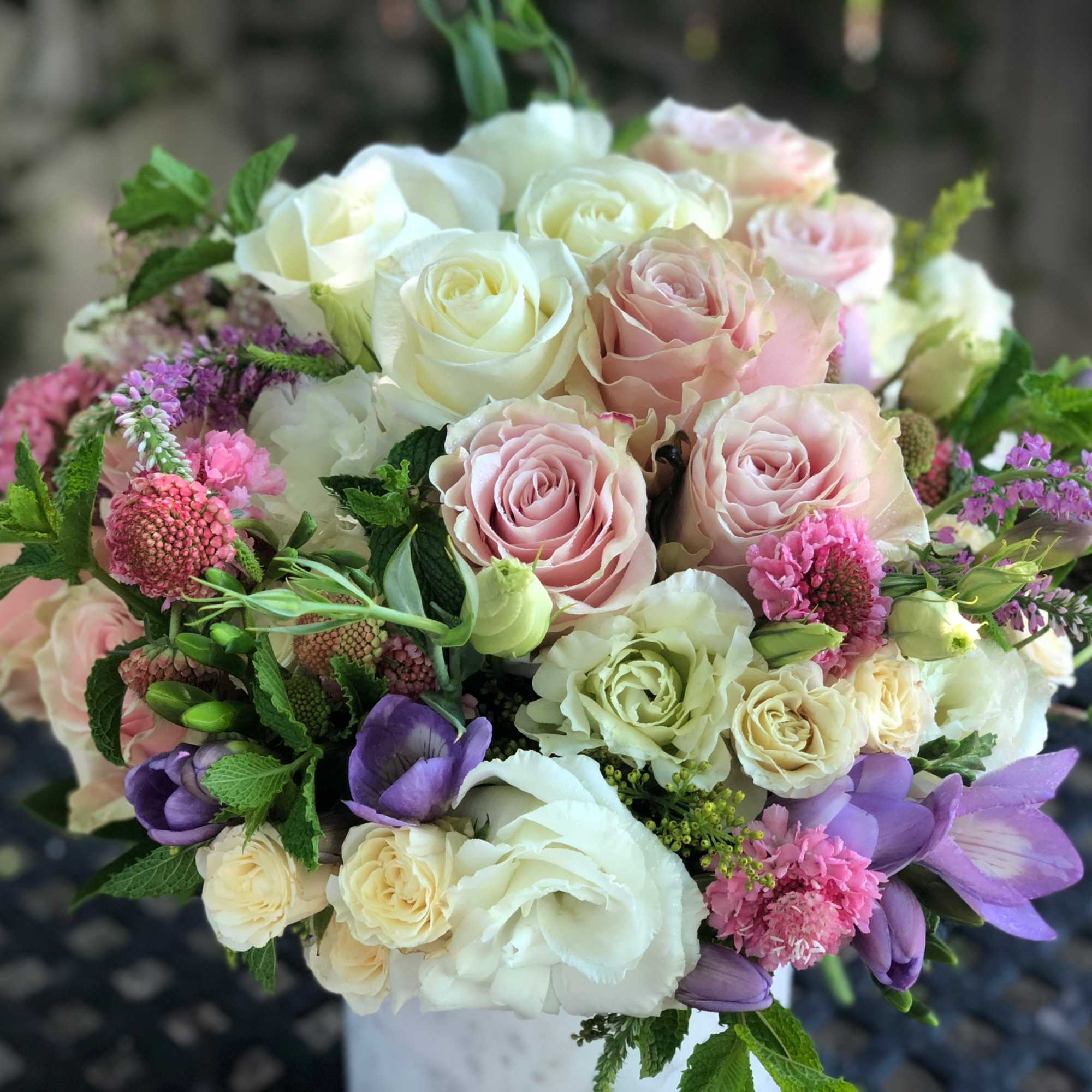Bouquet of pink, white, and purple roses with small accent flowers