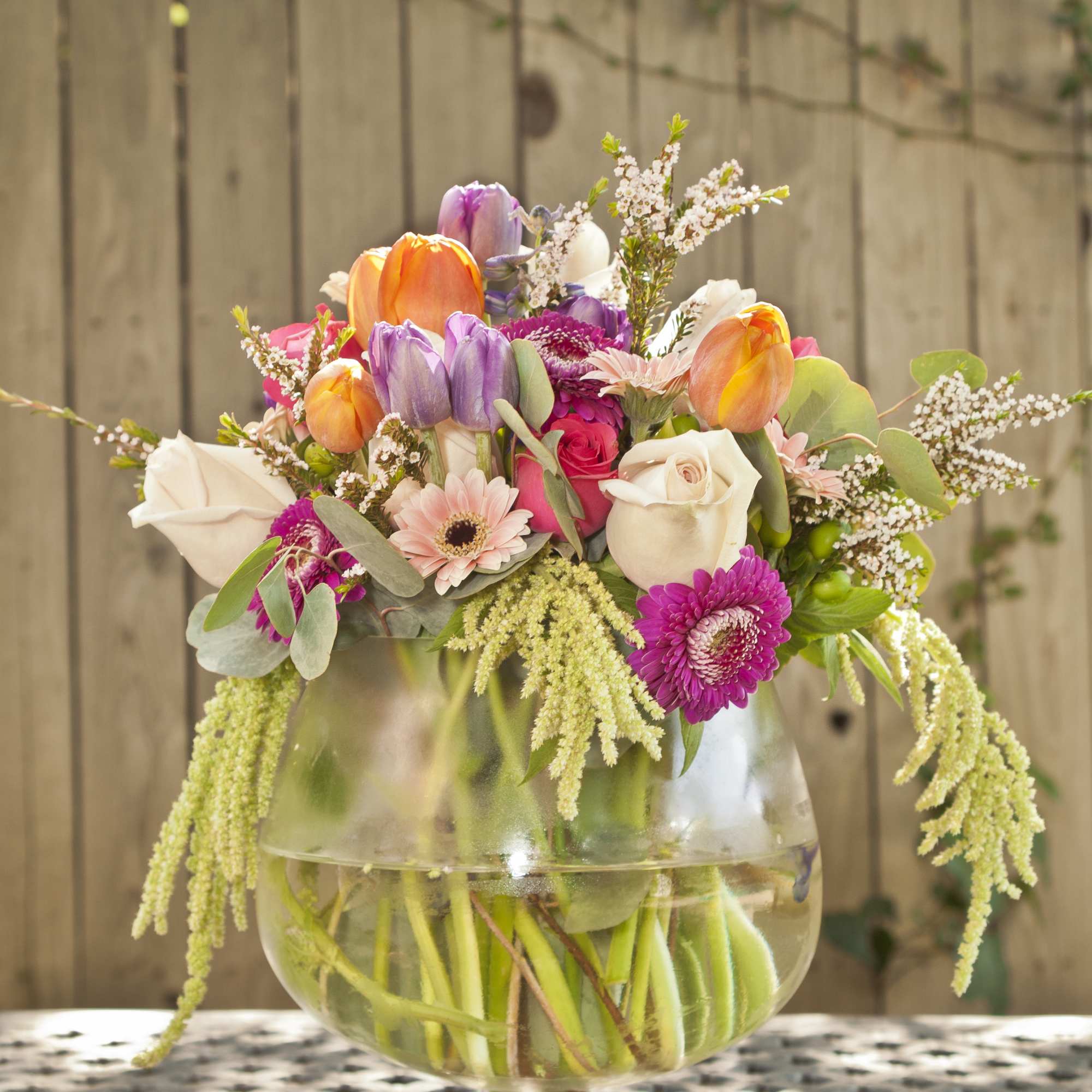 Mixed bouquet in a clear glass vase with orange, pink, purple, and white flowers