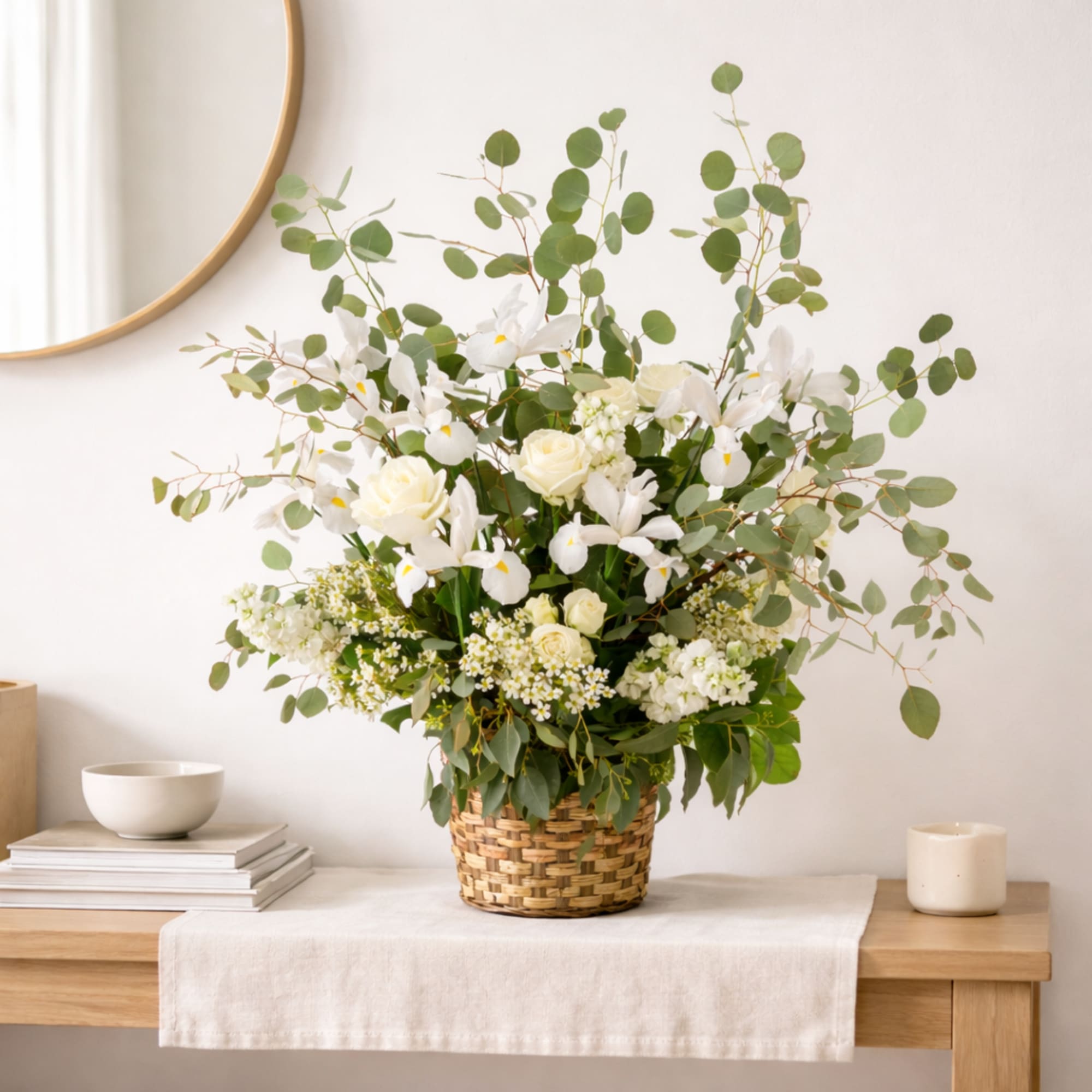A wispy white and green basket featuring silver dollar eucalyptus and white
