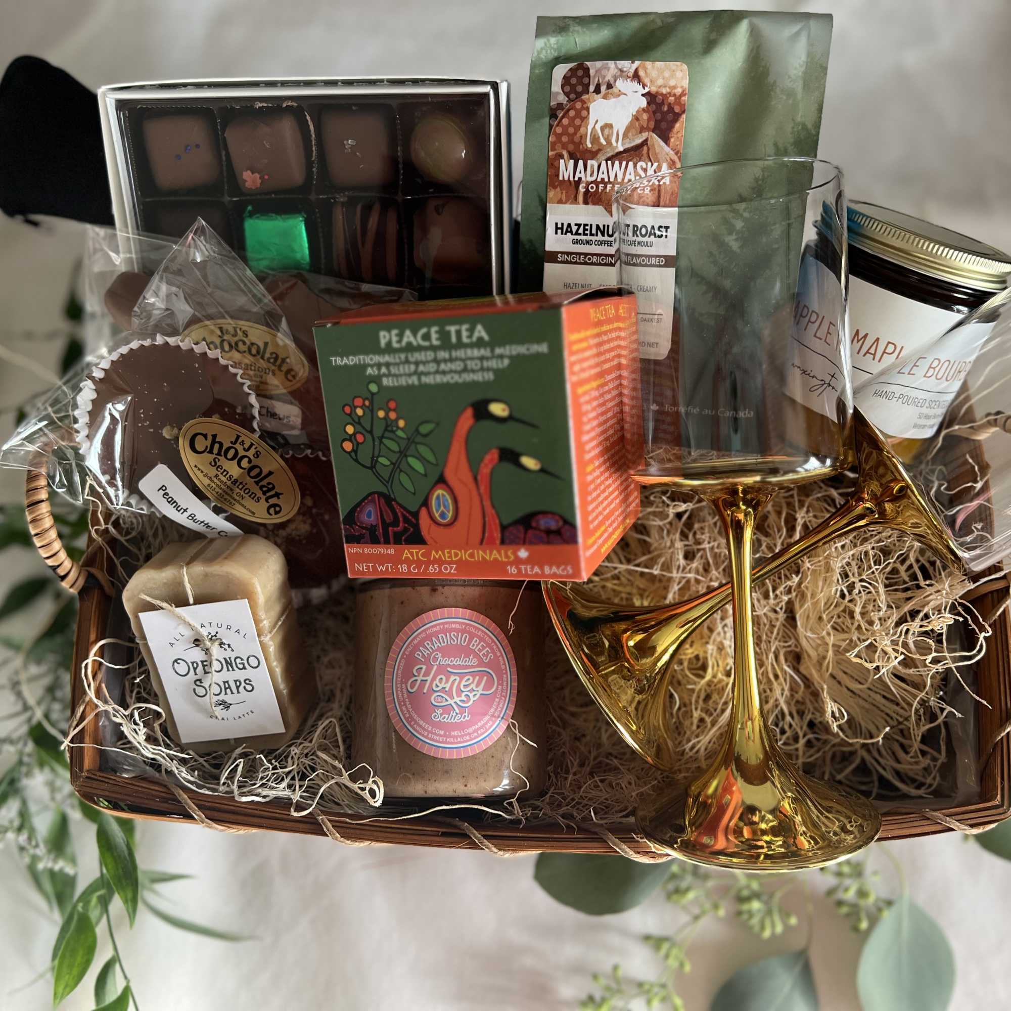 Gift basket with chocolates, tea, coffee, soap, honey, and two gold glasses