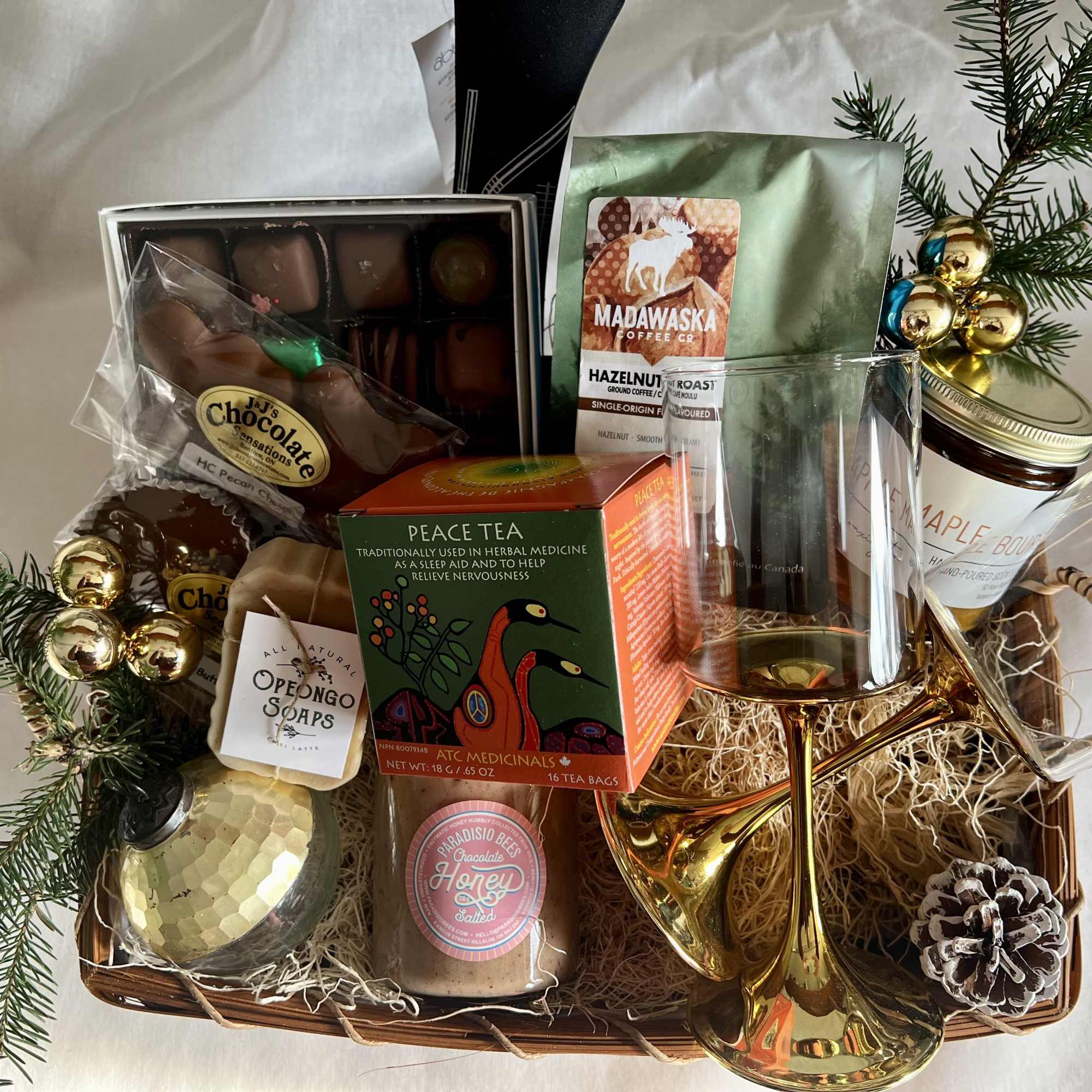 Gift basket with chocolates, tea, coffee, honey, soap, and a wine glass