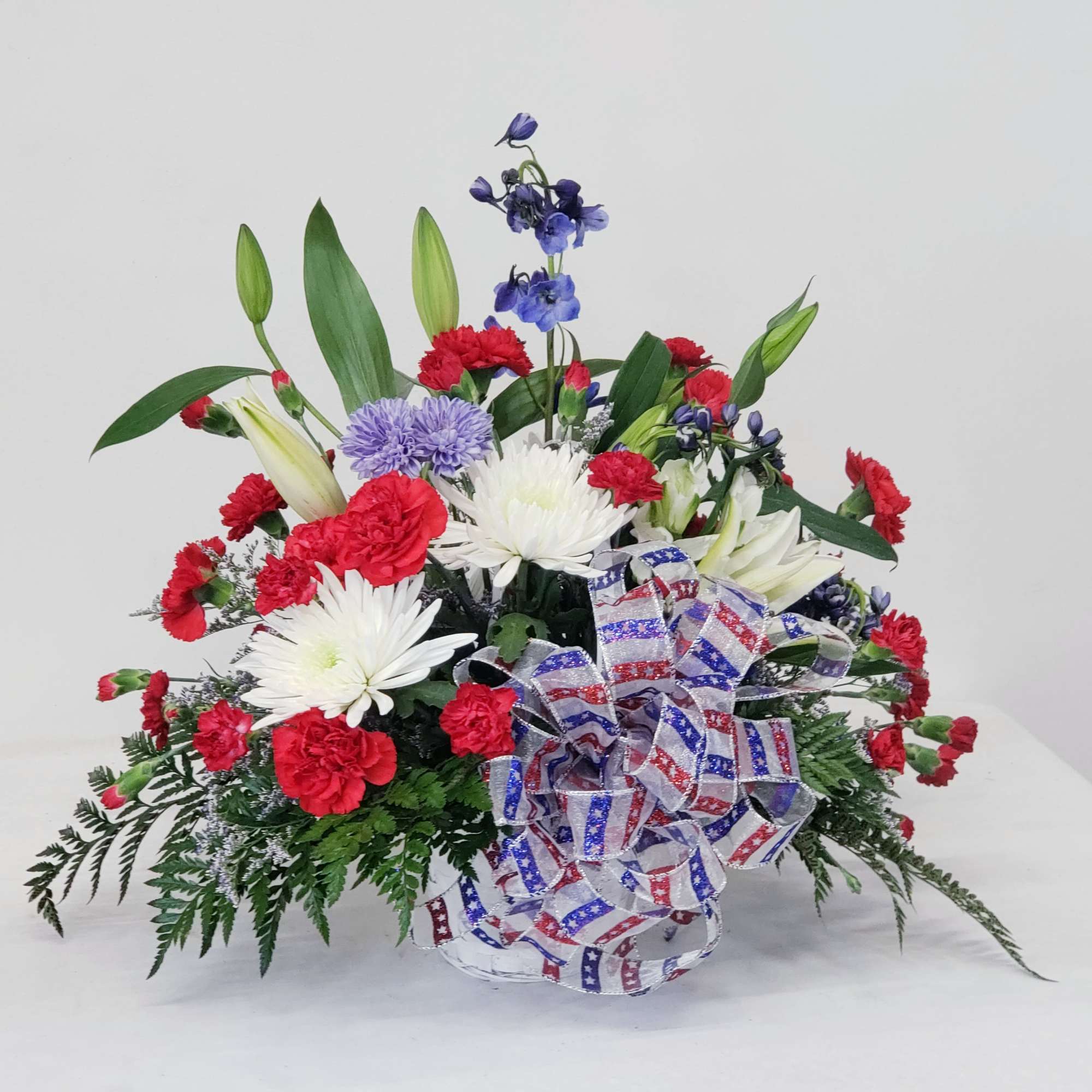 Red, white, and blue floral arrangement with a patriotic ribbon