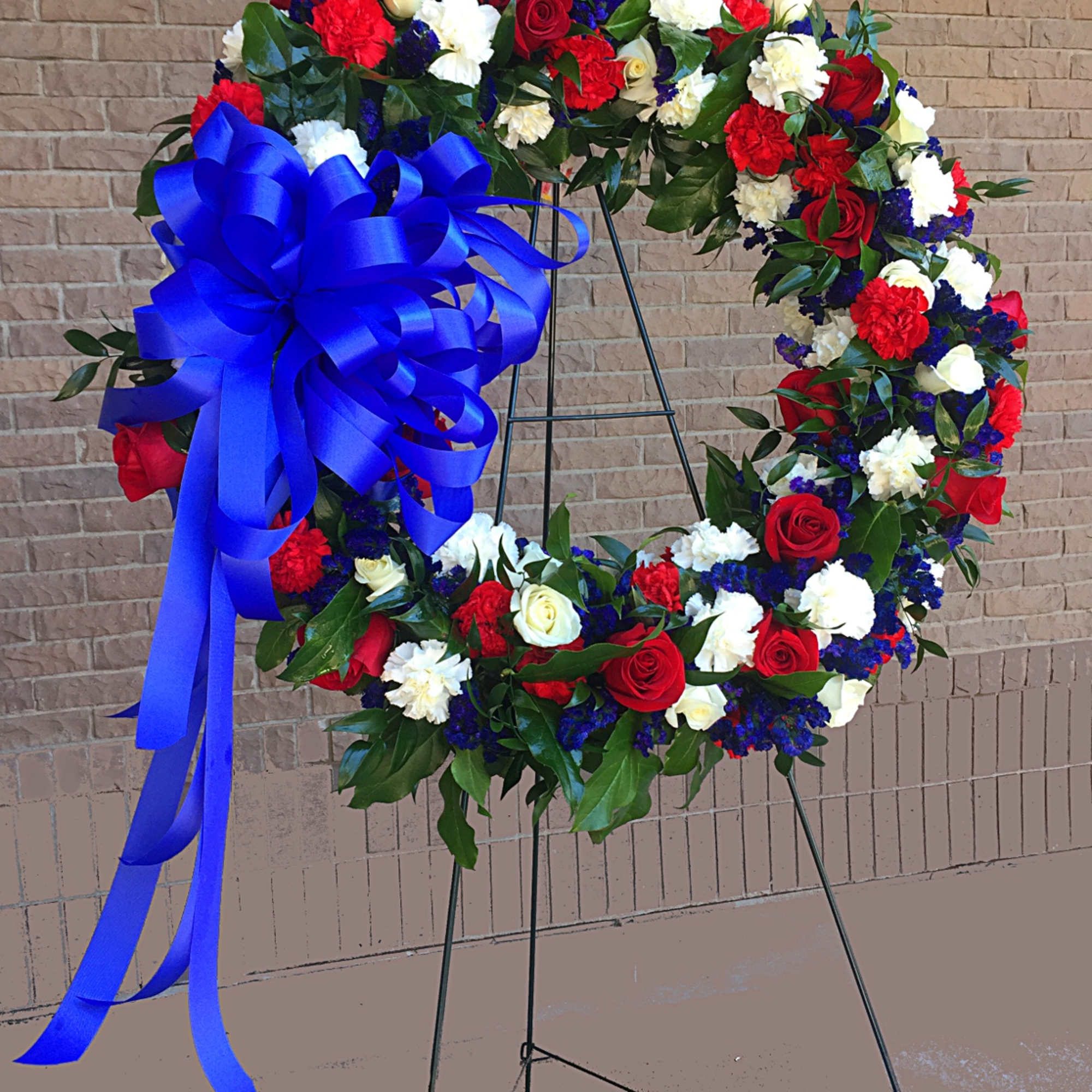 Circular floral wreath with red, white, and blue flowers on a stand