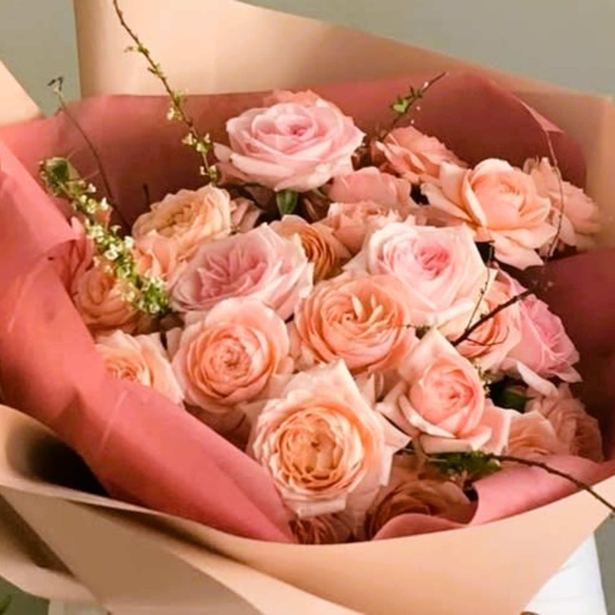 Bouquet of blush and peach roses wrapped in pink paper