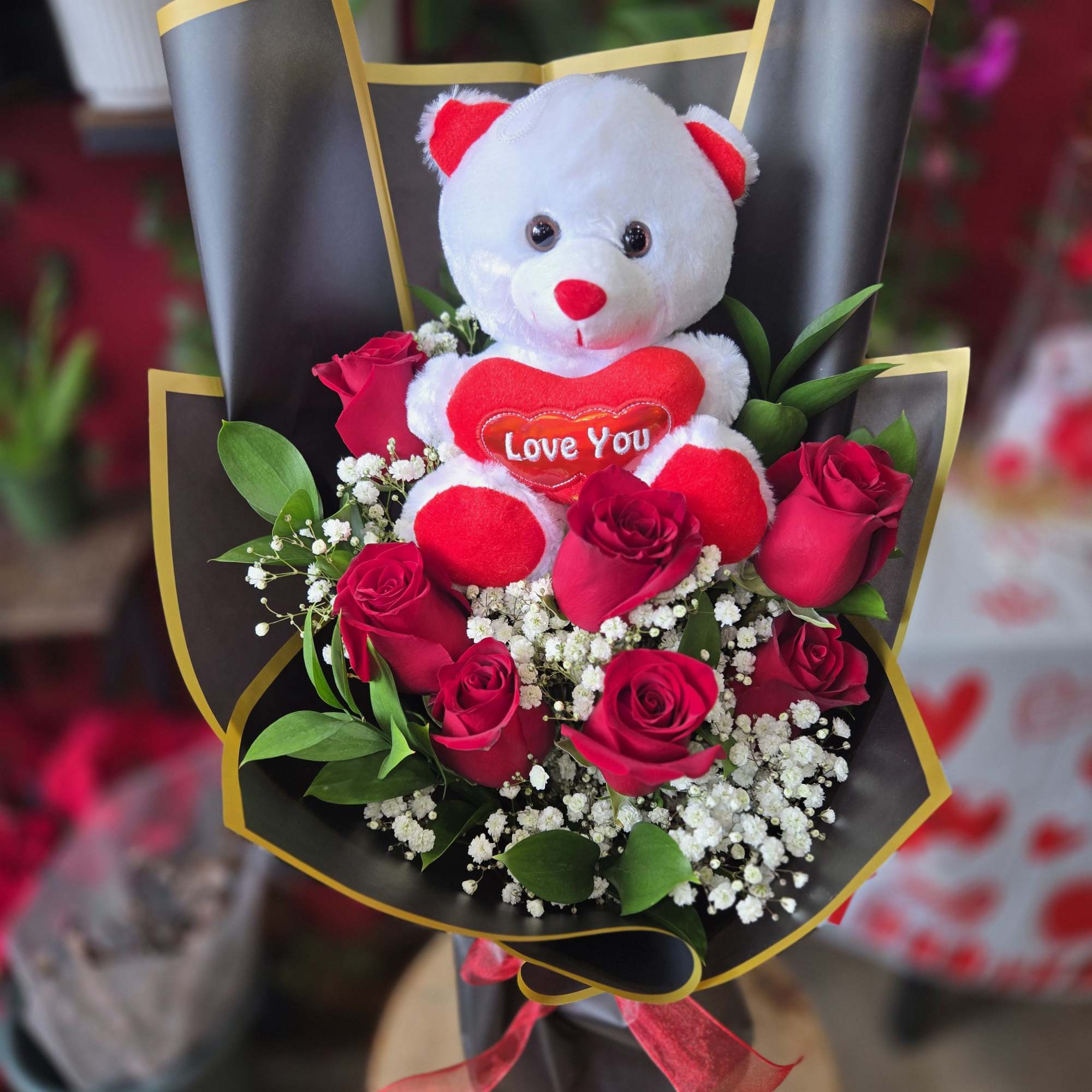 Bouquet of red roses with a teddy bear holding a heart