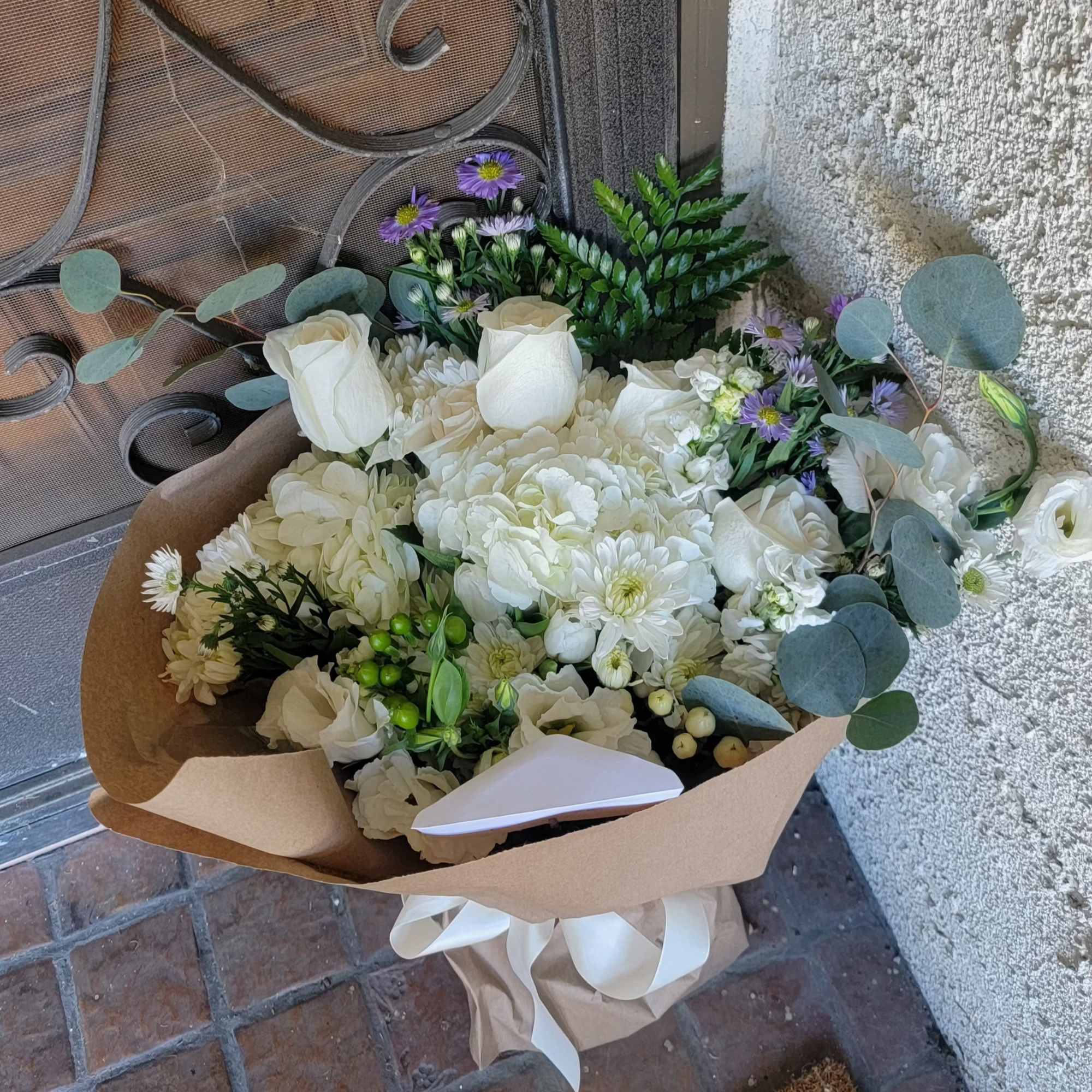 White rose and chrysanthemum bouquet with purple accent flowers and eucalyptus