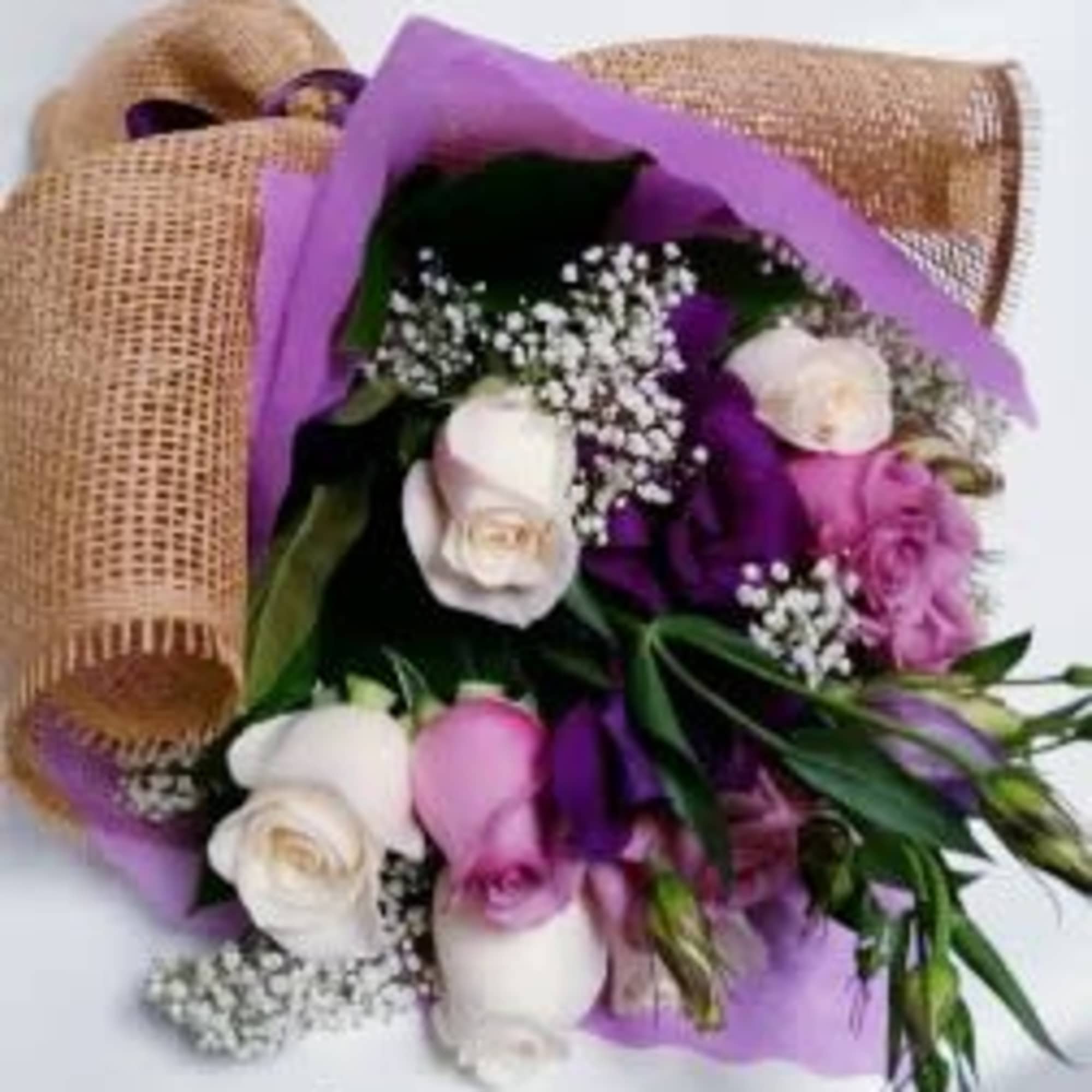 Bouquet of white and pink roses wrapped in purple paper and burlap
