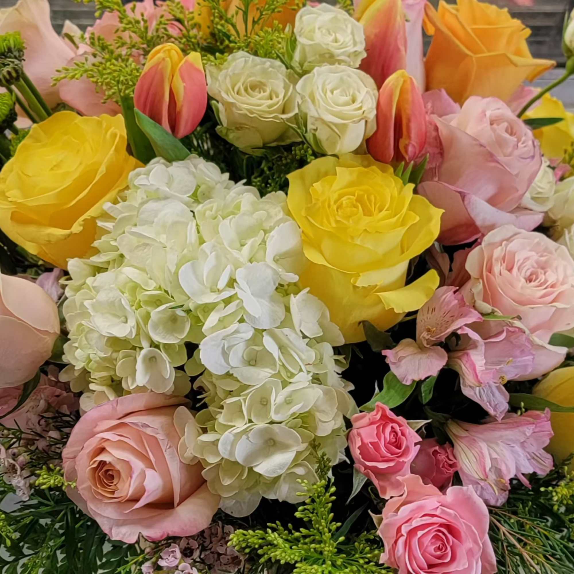 Bouquet of yellow, pink, and white roses with white hydrangea and tulips