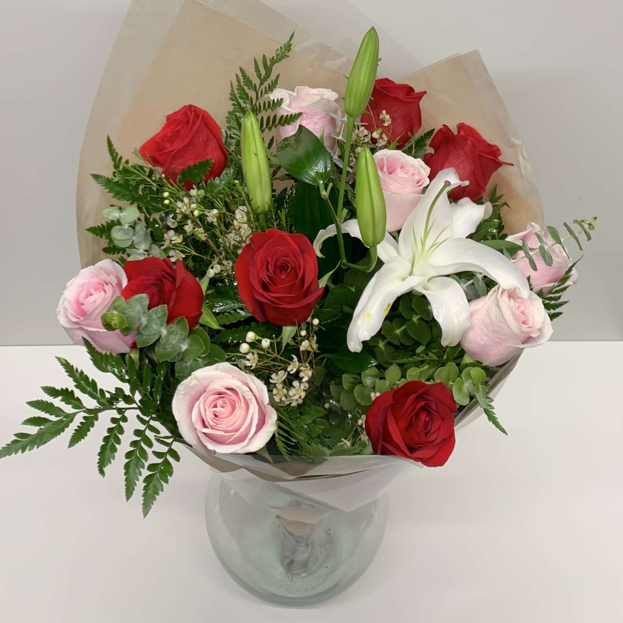 Bouquet of red and pink roses with a white lily in a glass vase