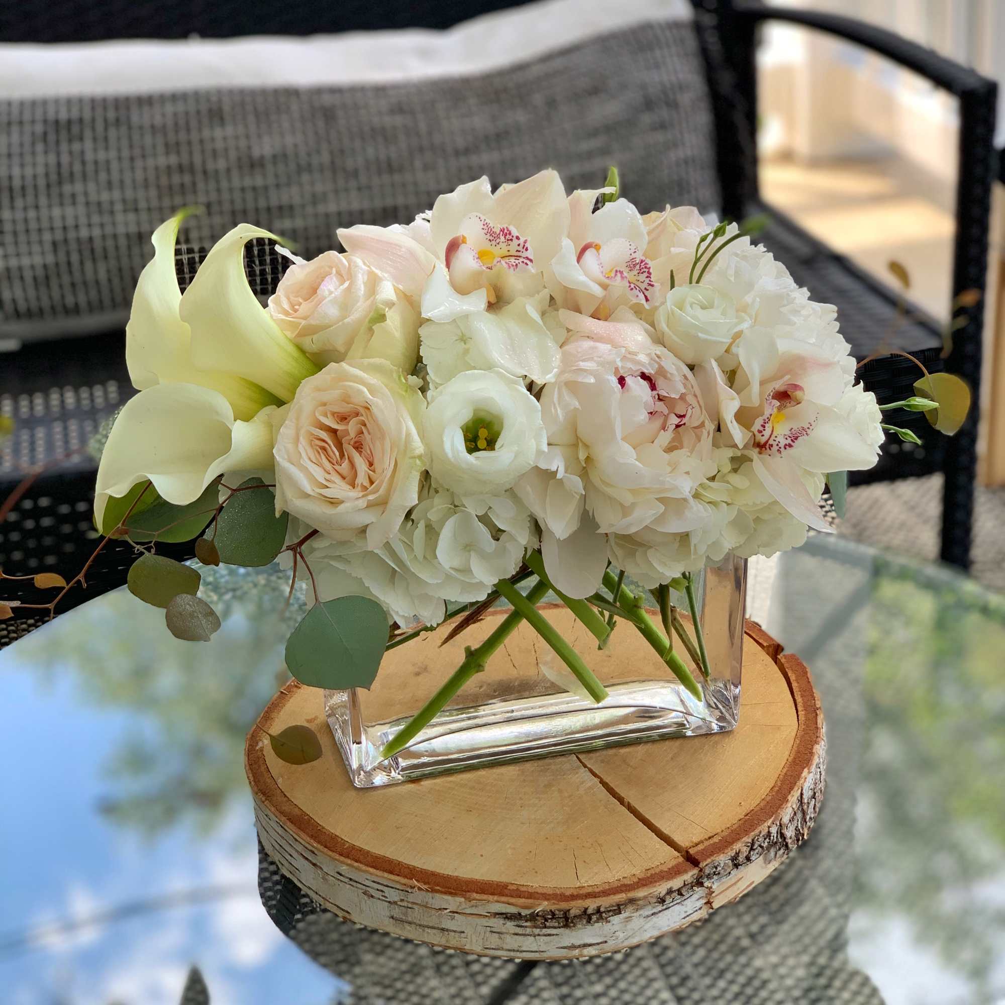 White and blush floral arrangement in a square glass vase