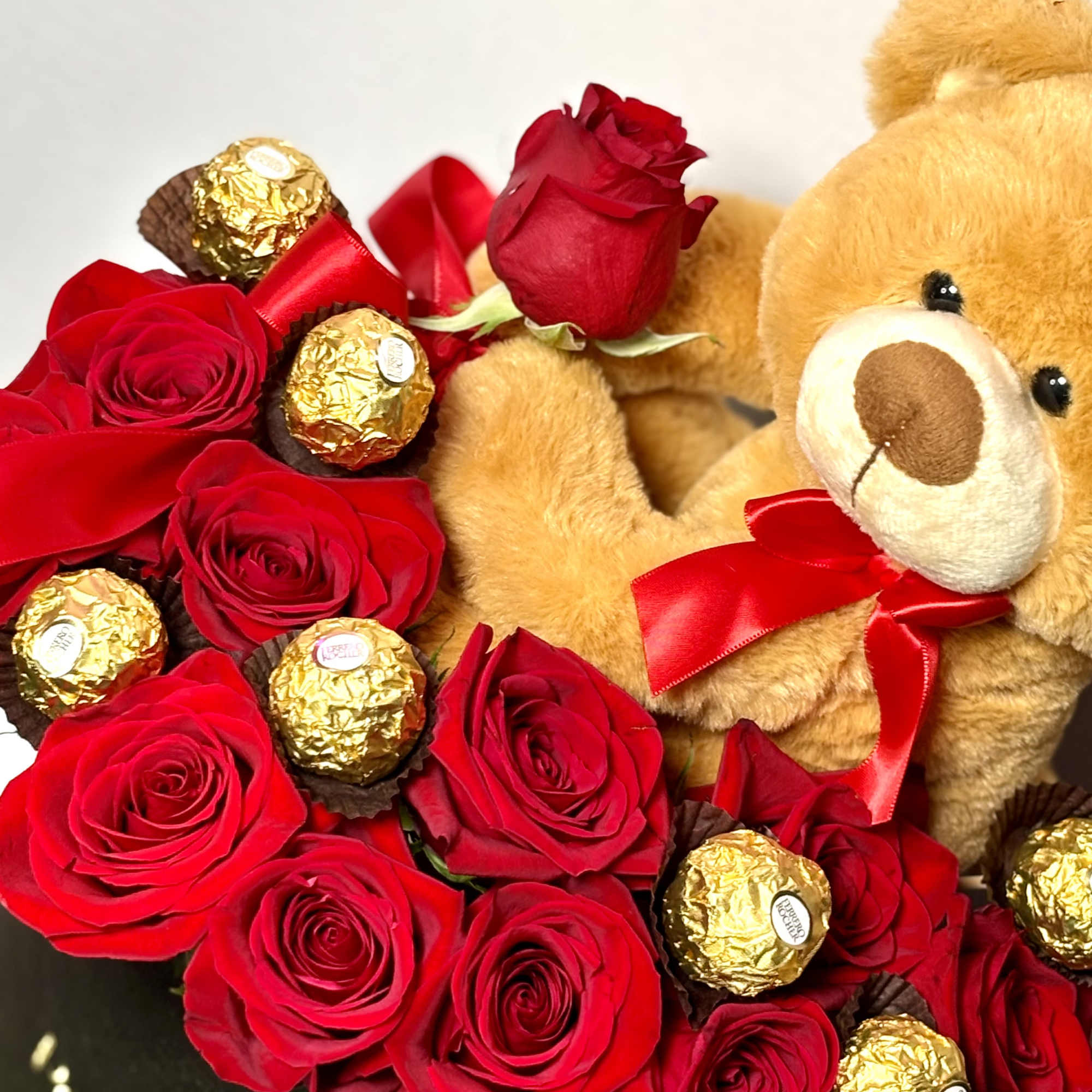 Red roses with gold-wrapped chocolates and a teddy bear