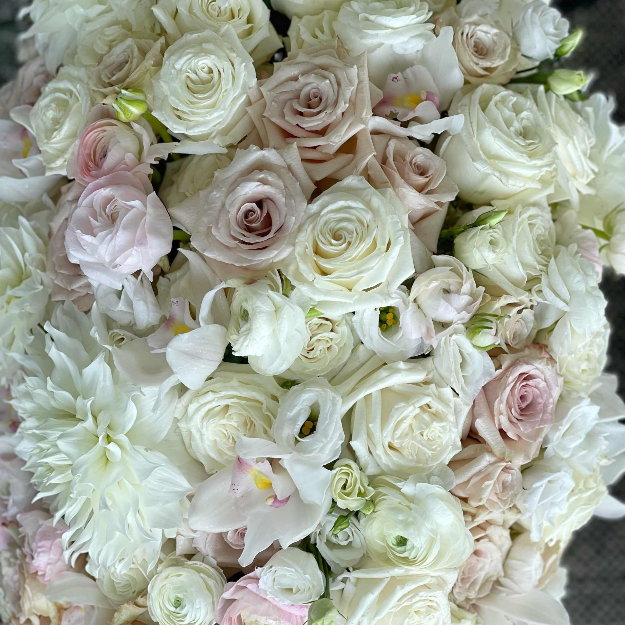 Dense bouquet of white and blush roses with white orchids