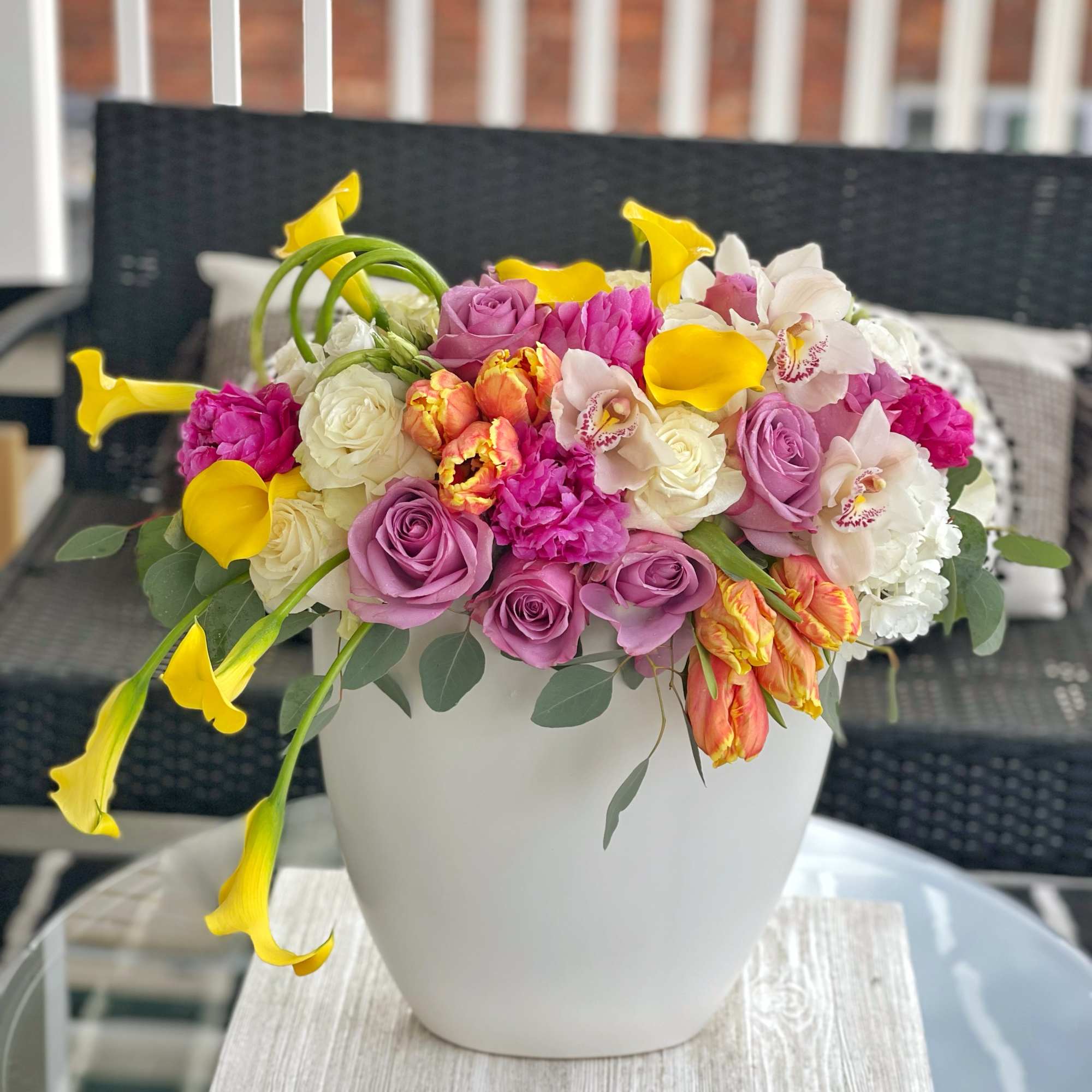 Colorful bouquet in a white vase with pink roses and yellow calla lilies