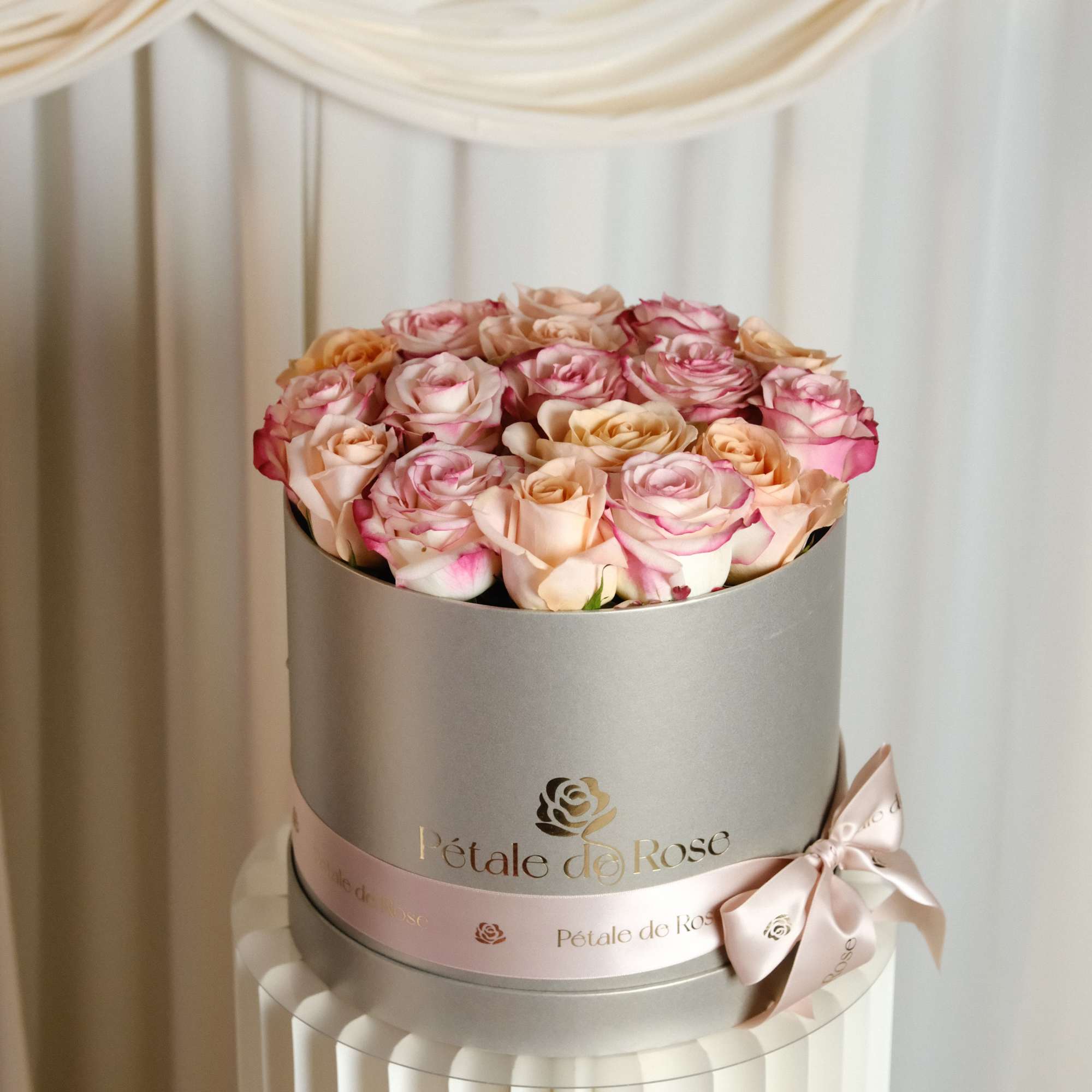 A delicate blend of ivory, and soft pink roses beautifully arranged in