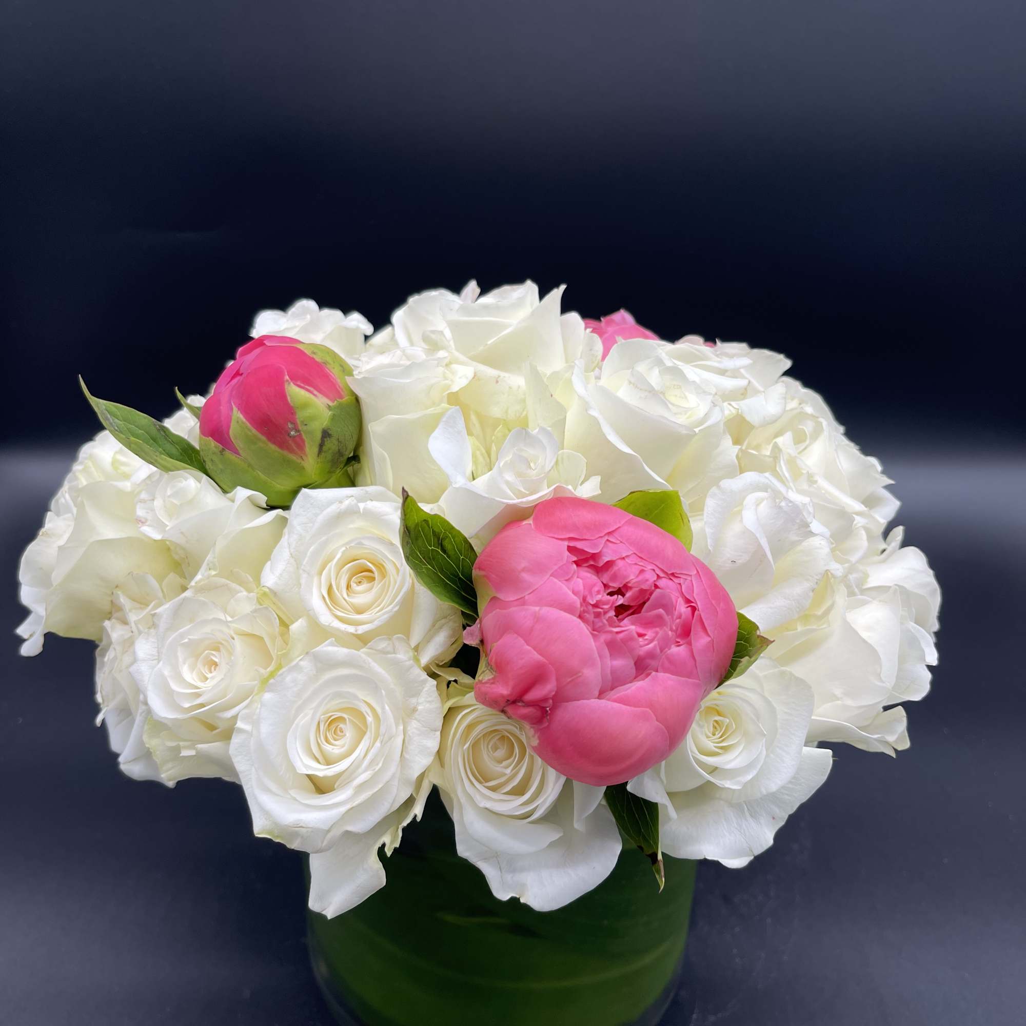 White and pink roses arranged in a green glass vase