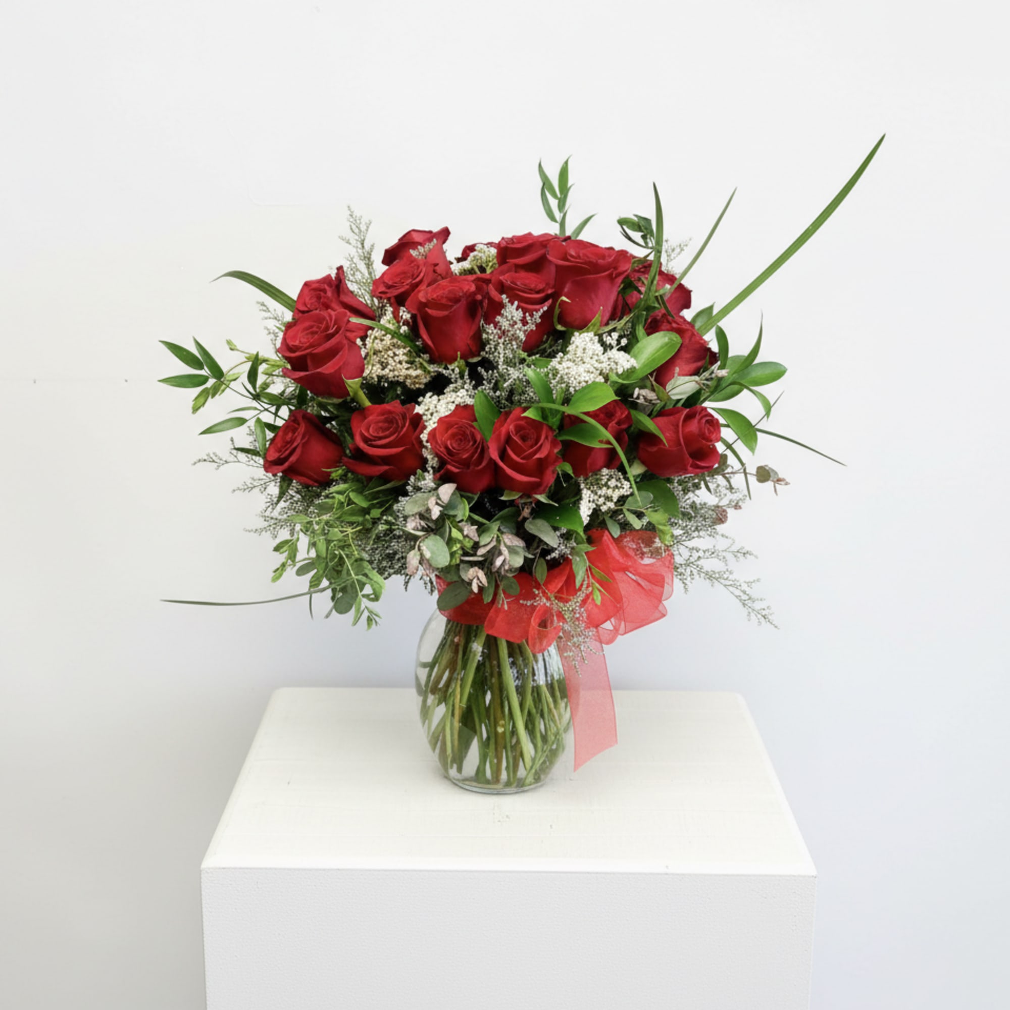 12 Red roses accented with premium greens in a  clear vase.