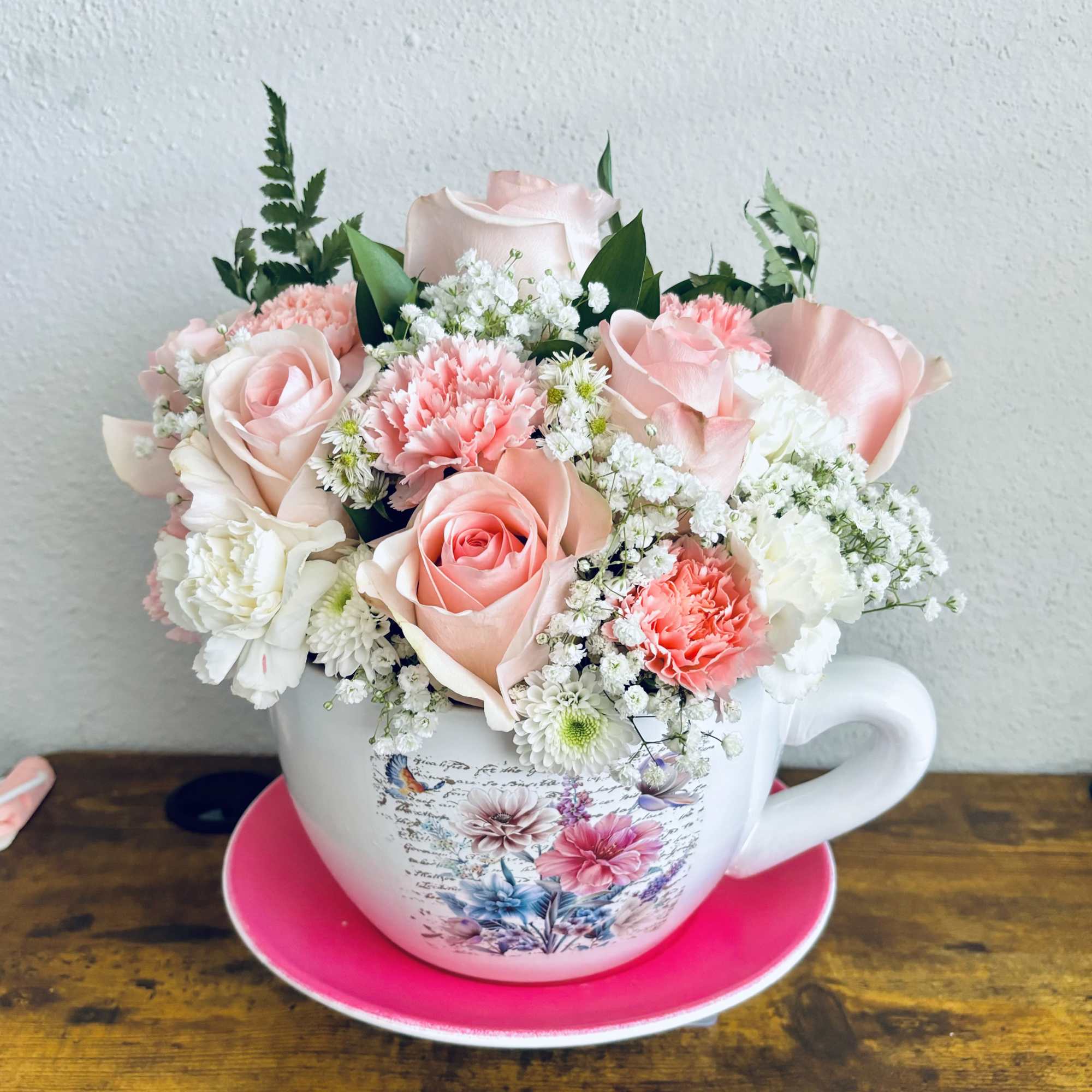 Pink and white bouquet arranged in a teacup on a saucer