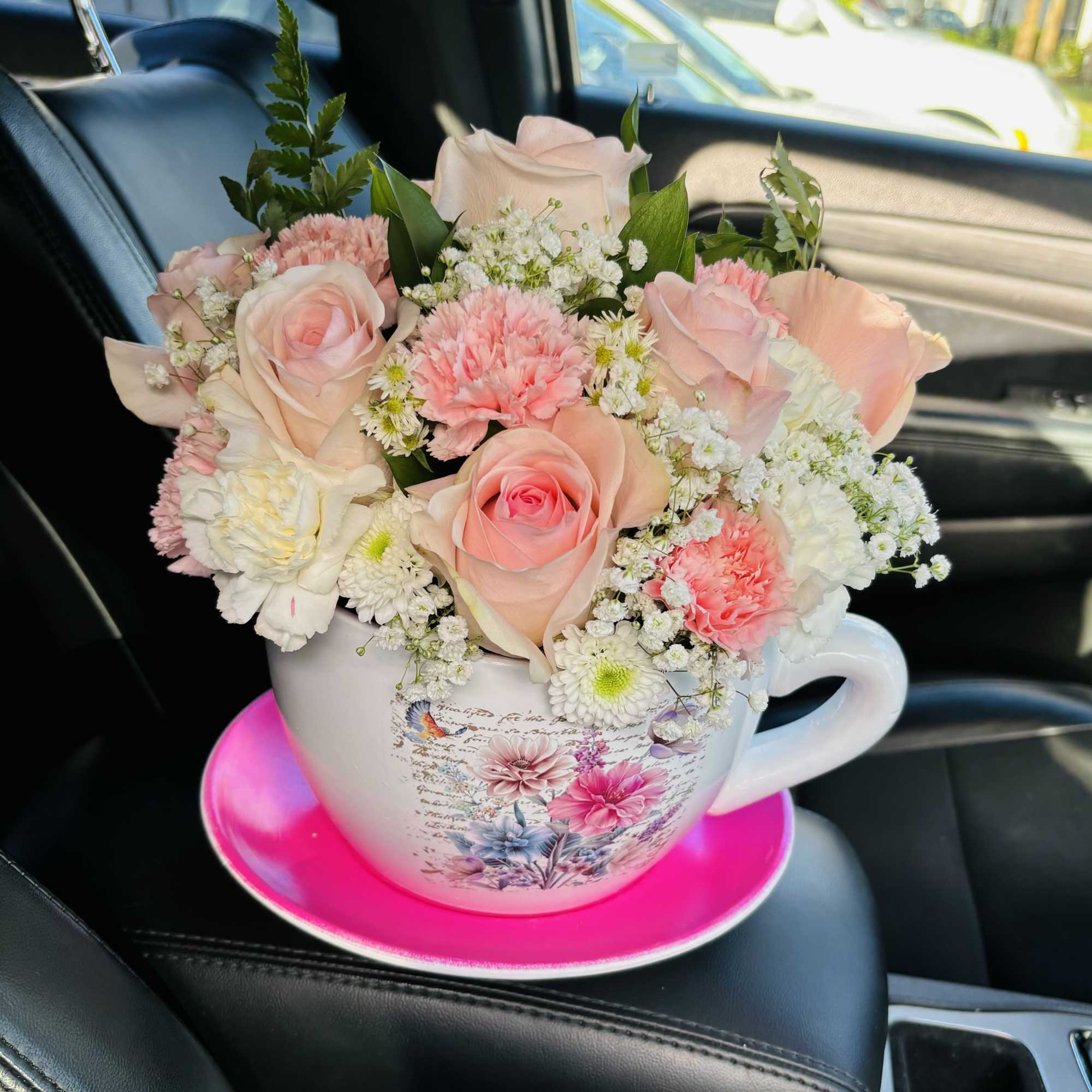 Pink and white bouquet in a decorative teacup on a bright saucer