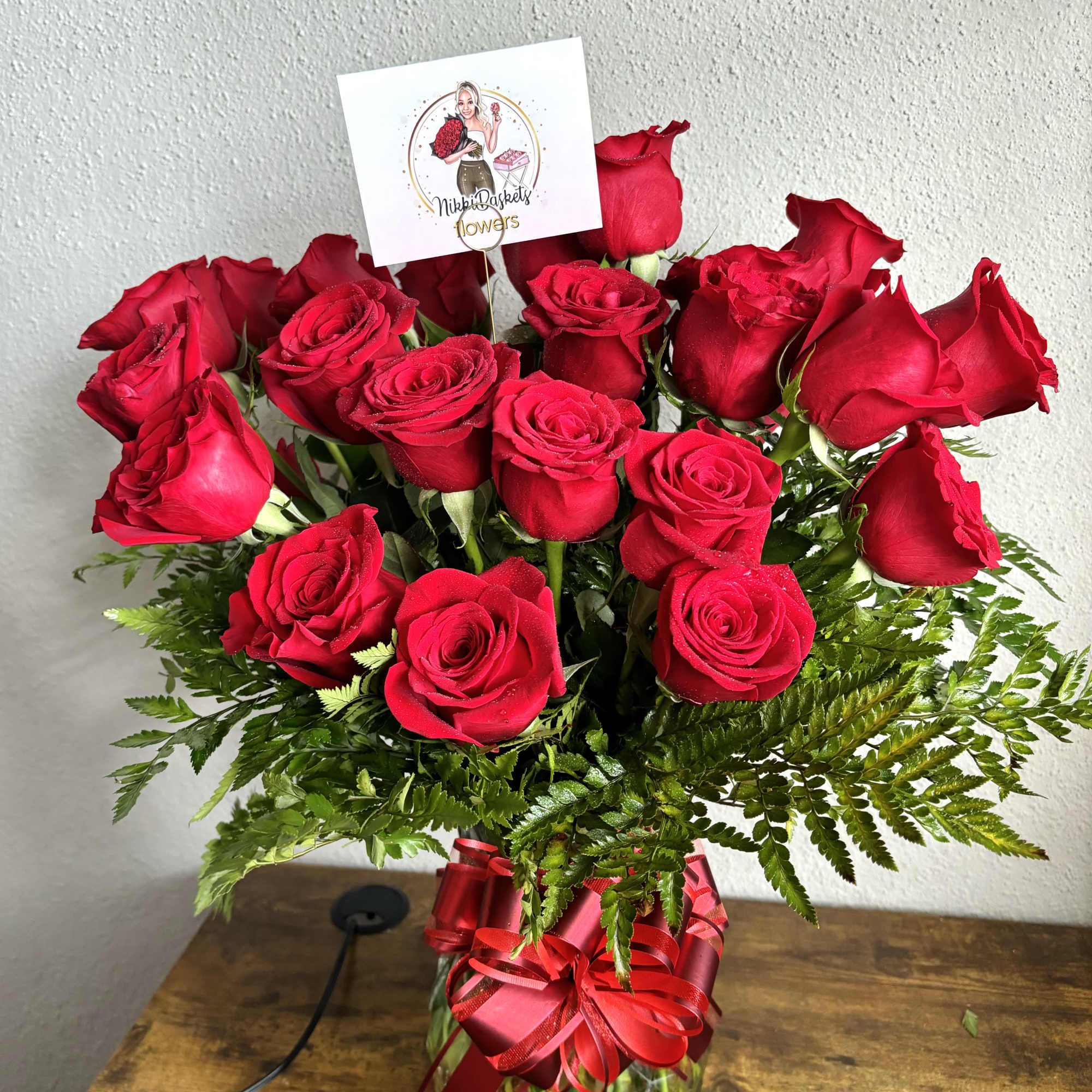 Red roses in a glass vase with a red ribbon bow