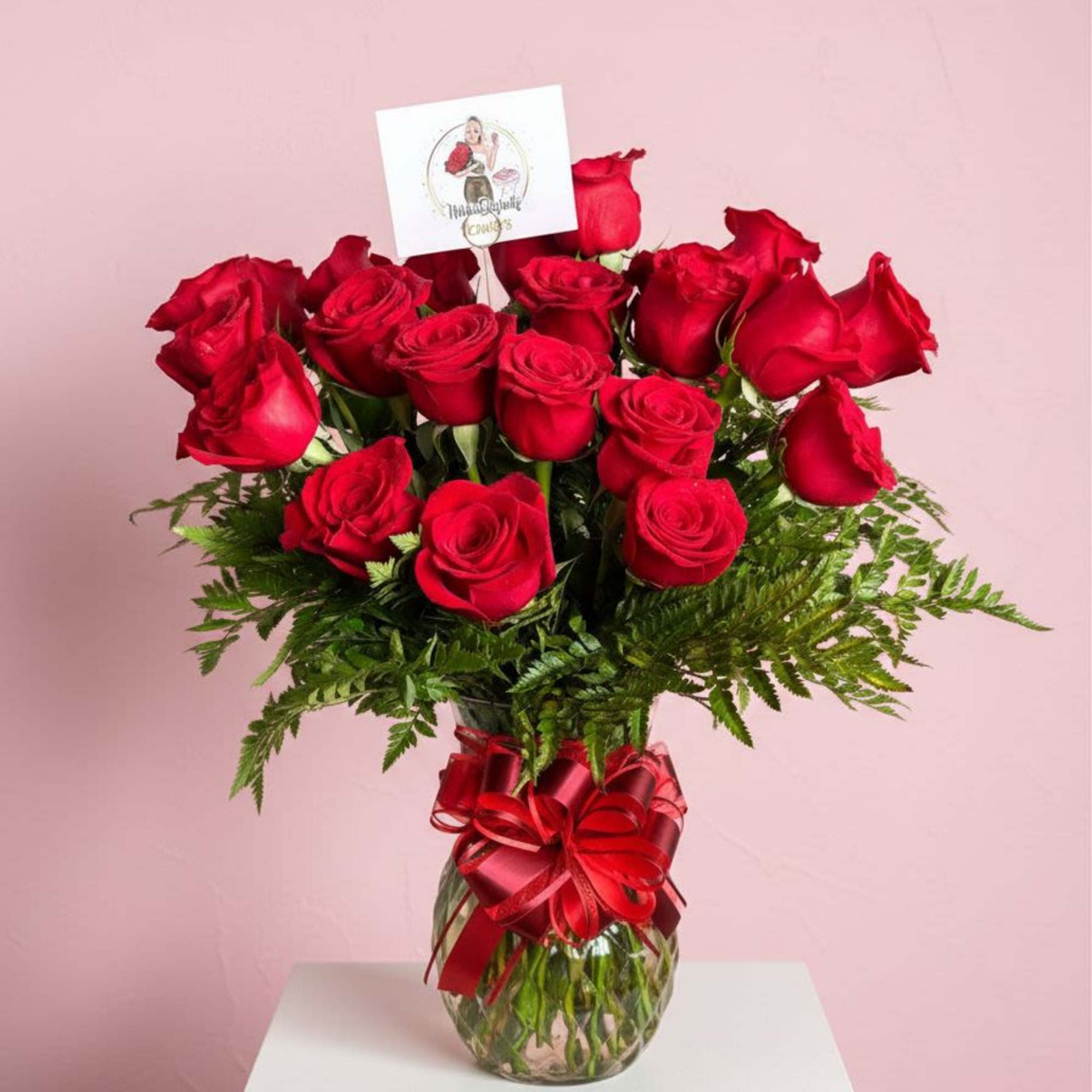 Red roses in a glass vase with a red ribbon bow