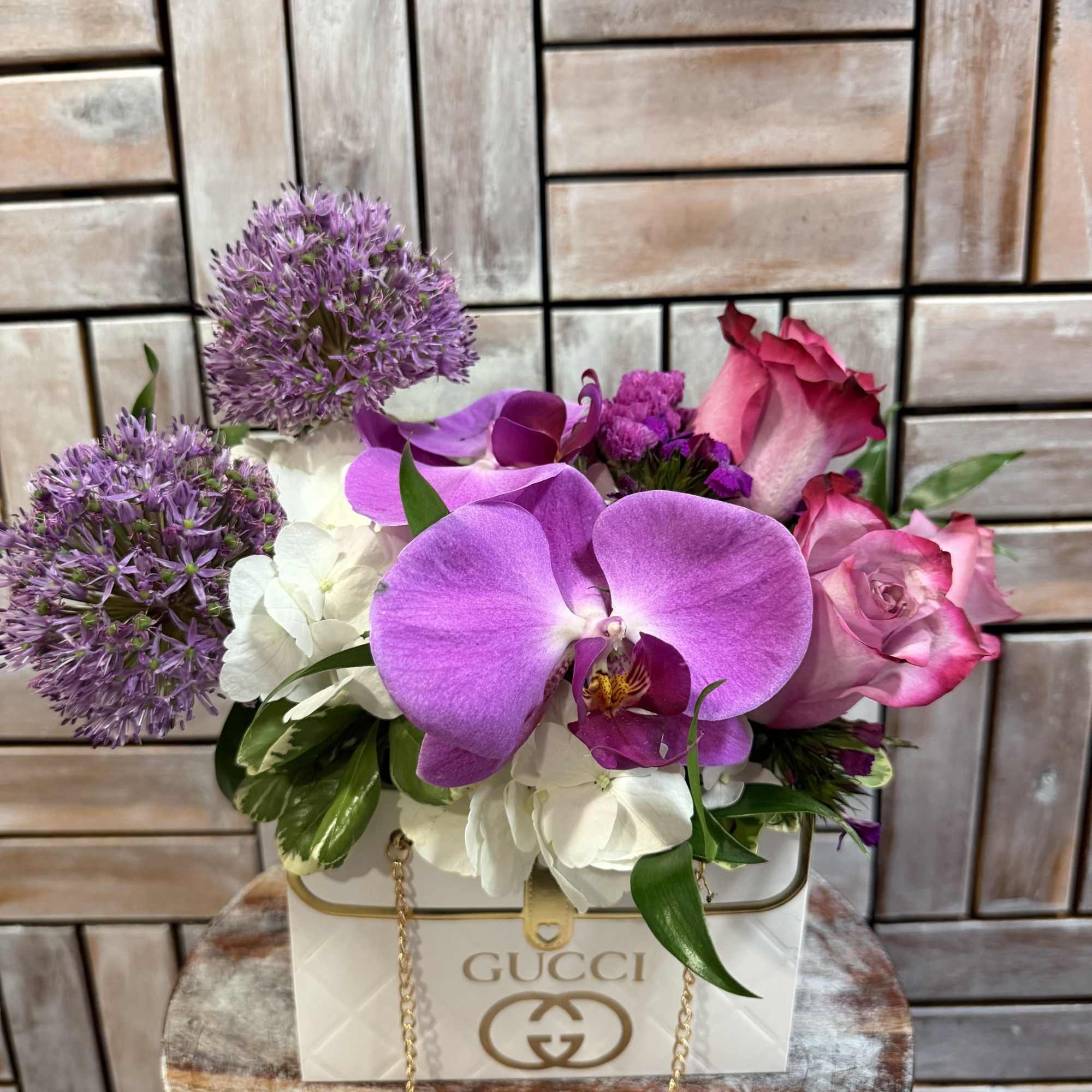 A luxurious floral arrangement designed in an elegant, designer-inspired, keepsake handbag container.
