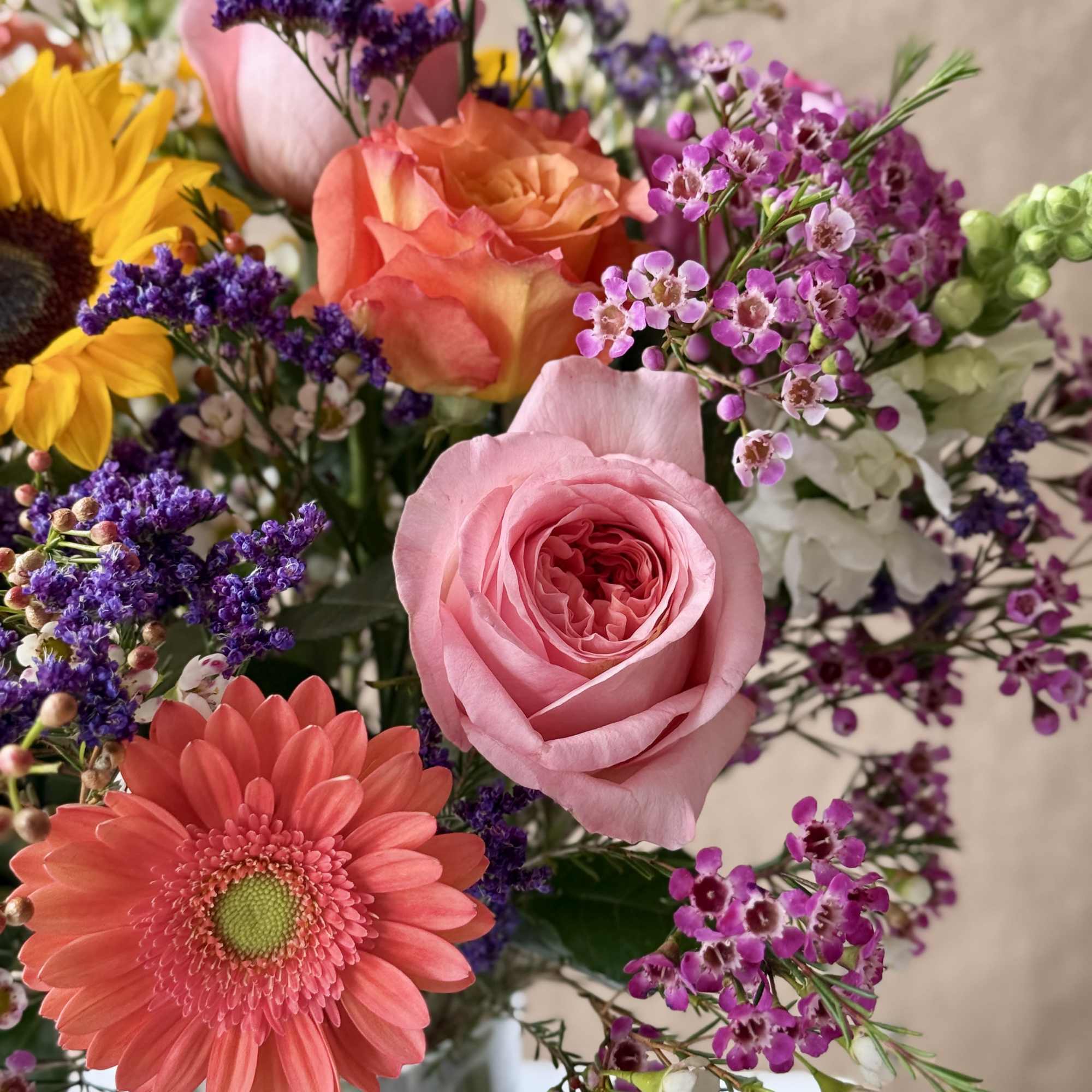 Mixed bouquet with pink roses, coral gerbera daisies, and purple filler flowers