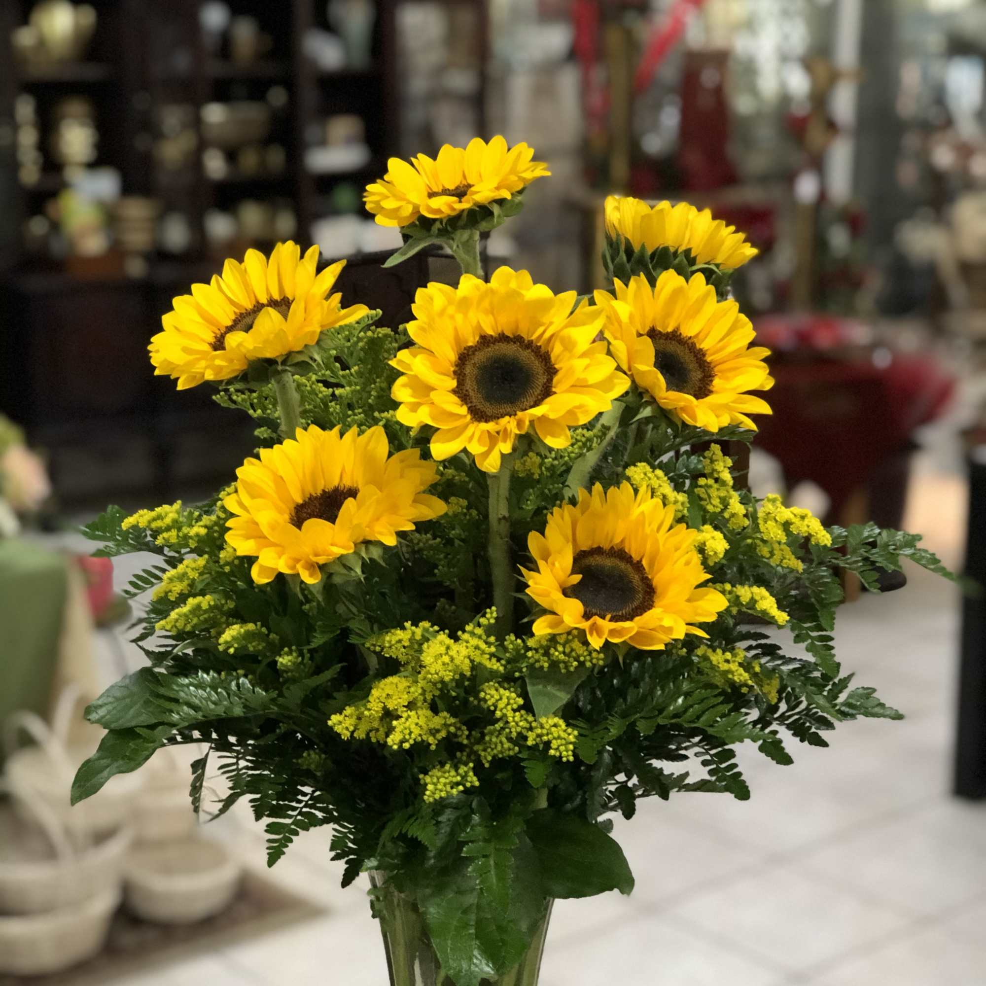 Tall arrangement of bright yellow sunflowers in a clear glass vase