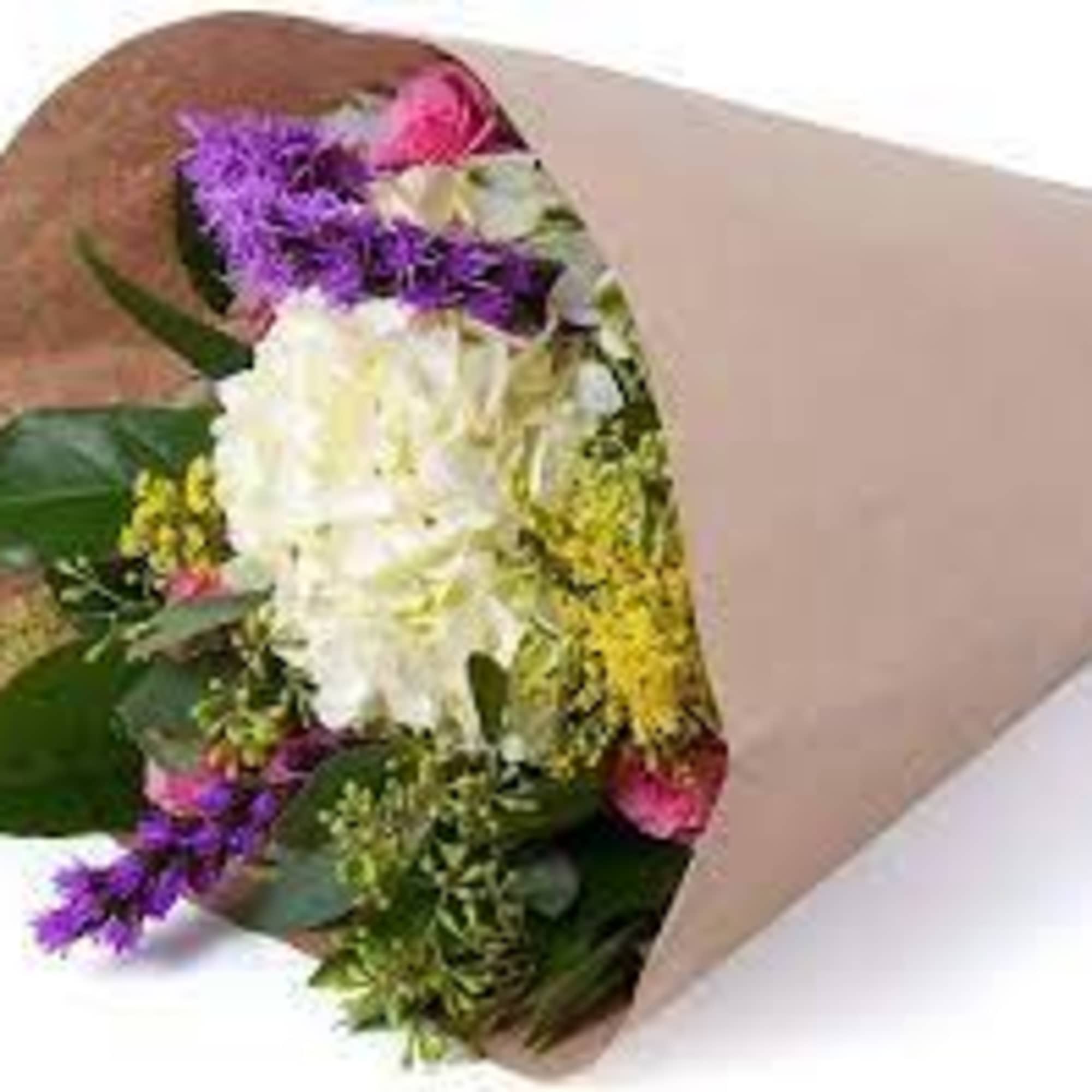 Hand-tied bouquet with white hydrangea, purple flowers, and yellow accents wrapped in kraft paper